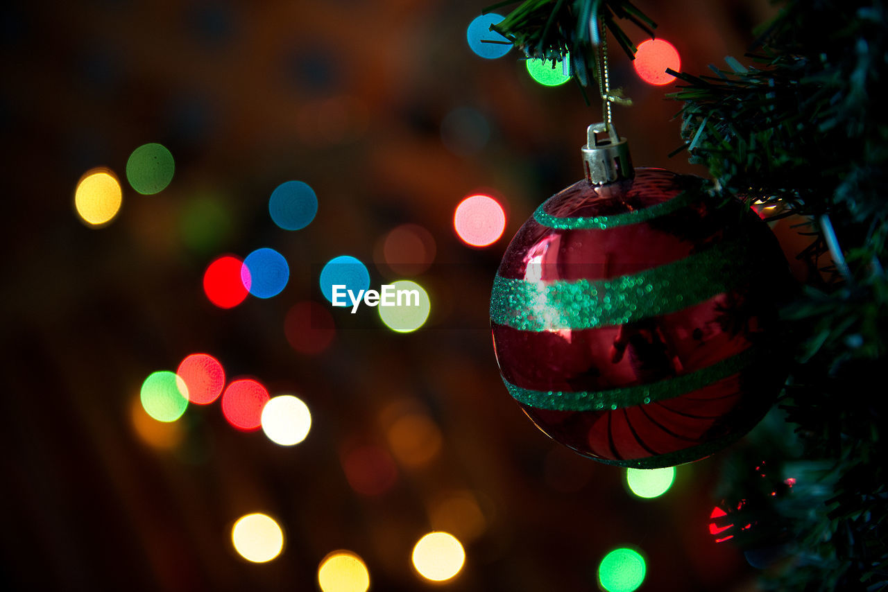 Defocused image of christmas bauble against illuminated christmas lights