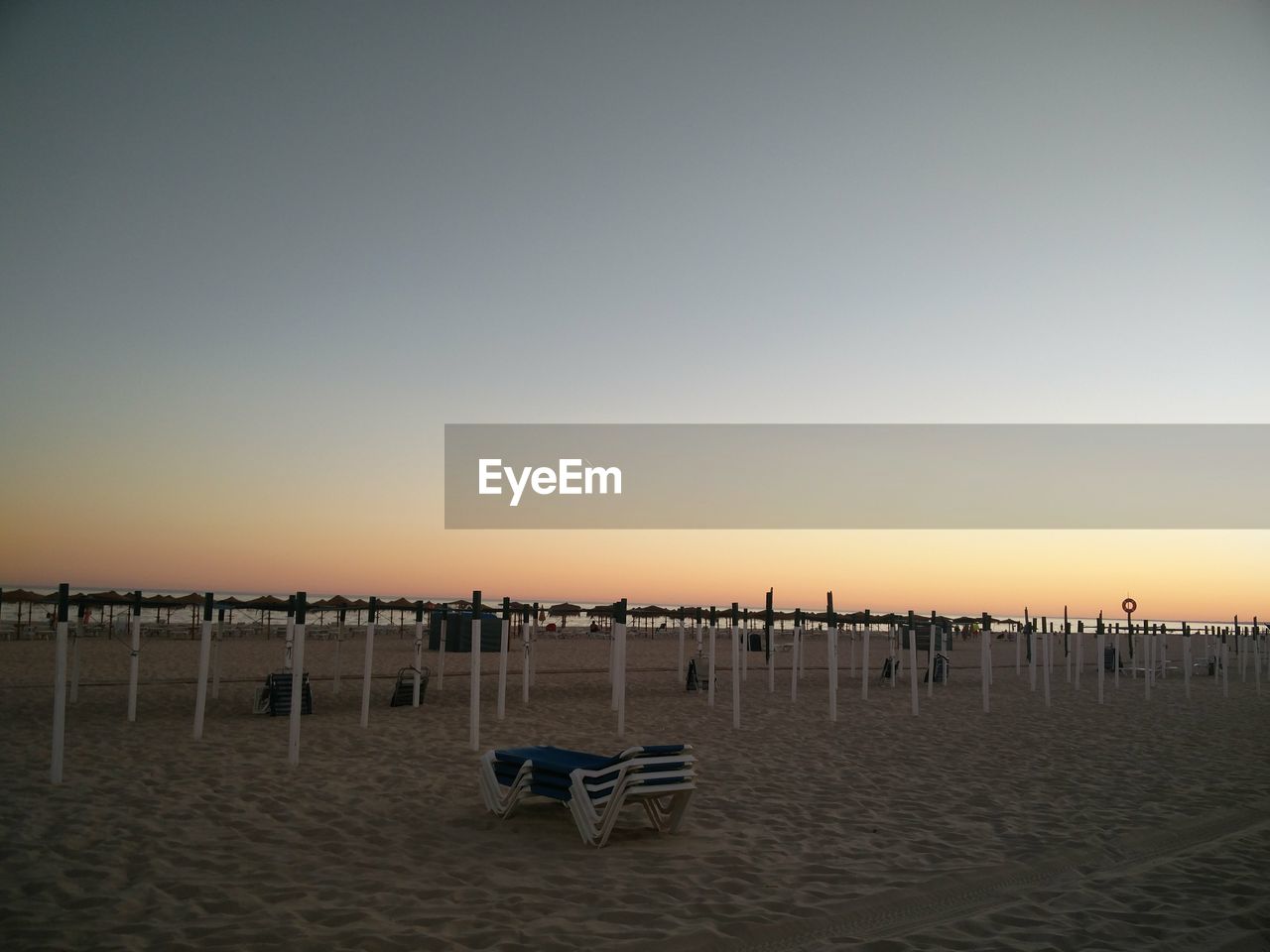 DECK CHAIRS ON BEACH AGAINST CLEAR SKY