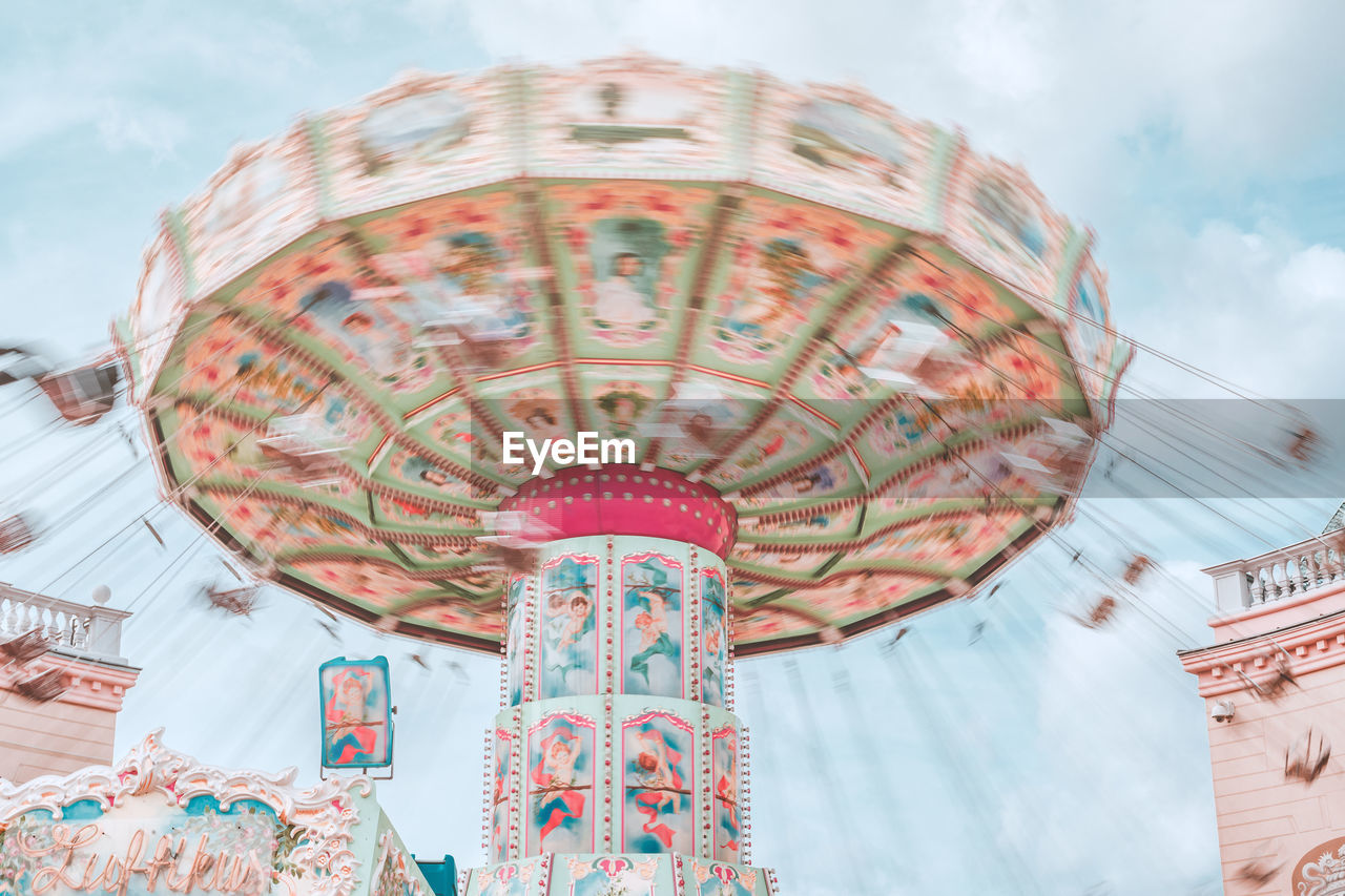 Low angle view of spinning carousel against sky