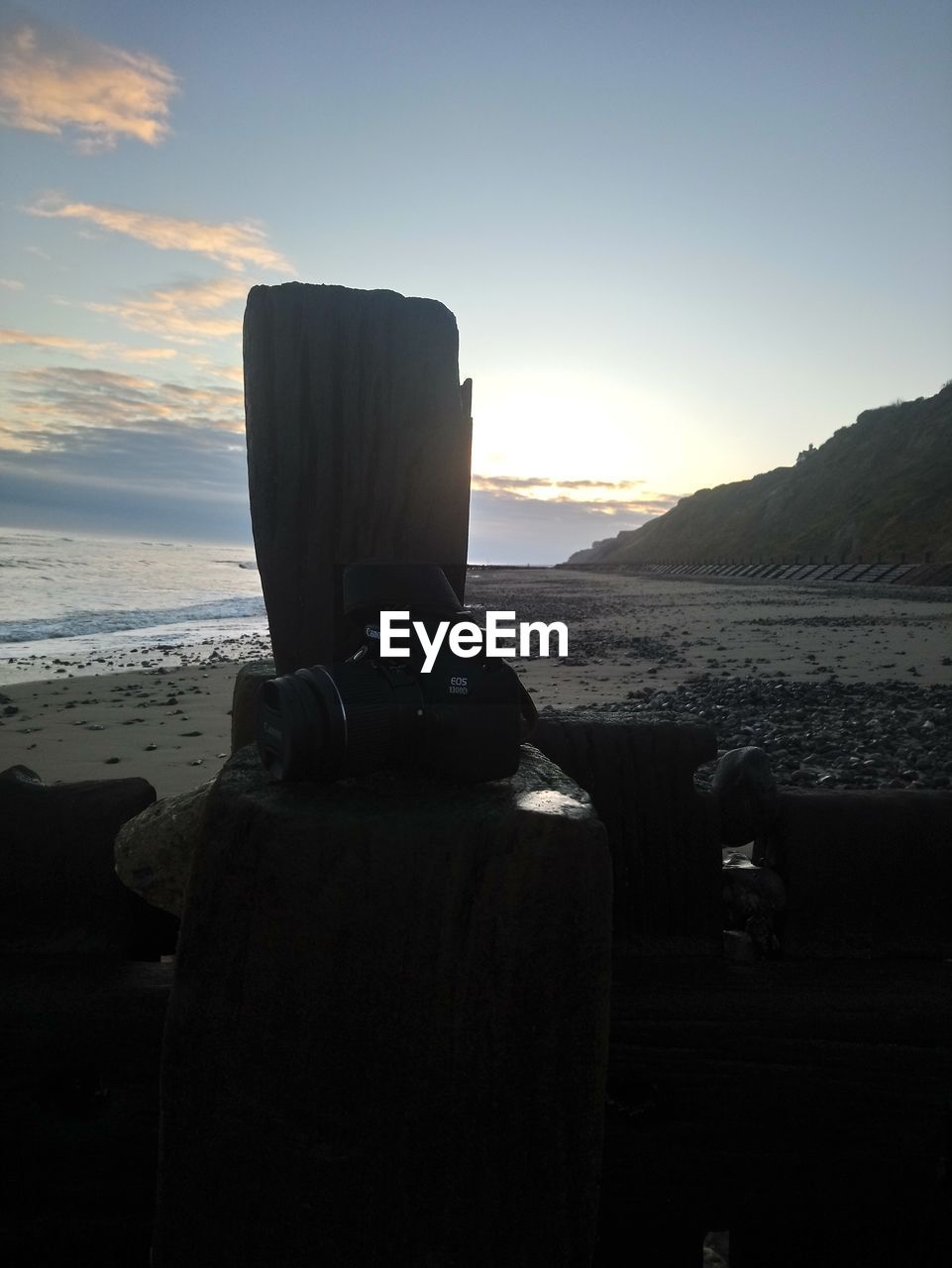 CLOSE-UP OF MOBILE PHONE AT BEACH AGAINST SKY