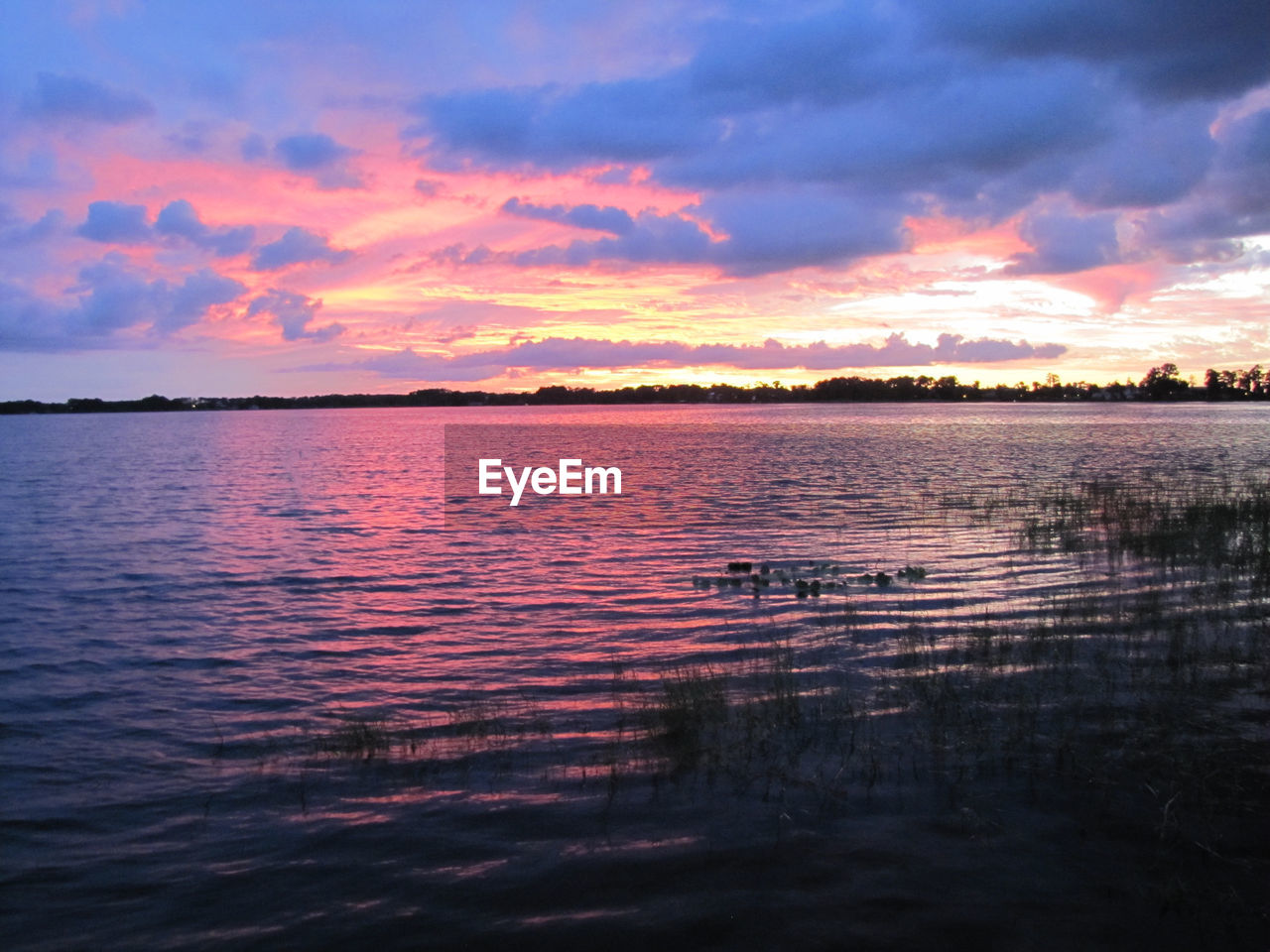 Scenic view of lake against sky at sunset