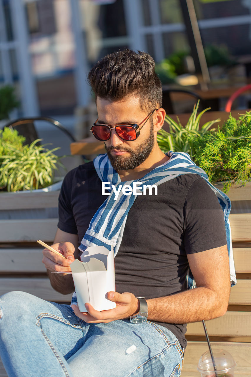 YOUNG MAN SITTING WITH ICE CREAM IN RESTAURANT