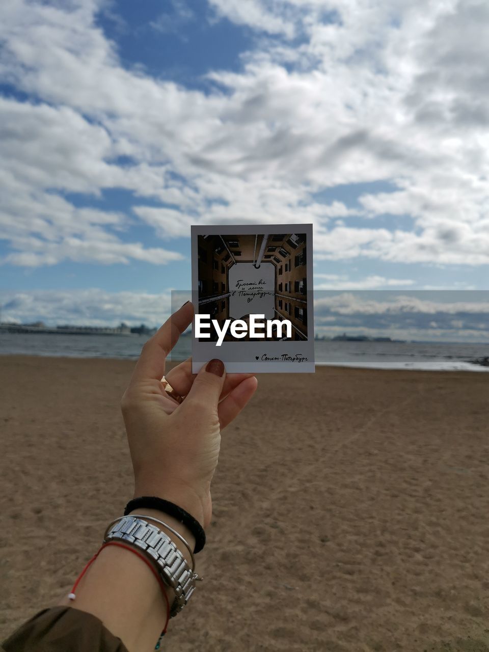 LOW SECTION OF MAN HOLDING TEXT ON BEACH