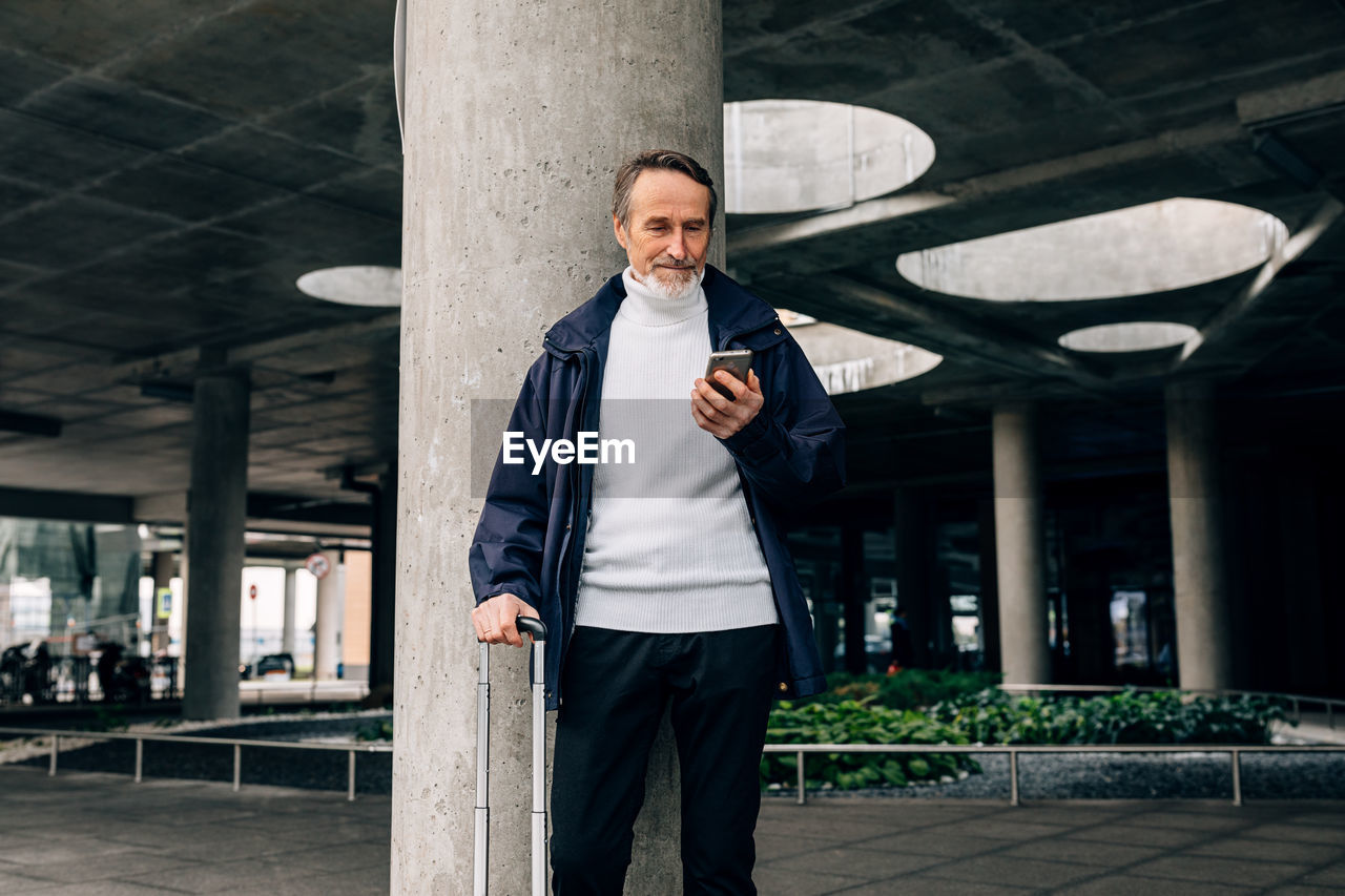 Senior man using smart phone while standing outdoors