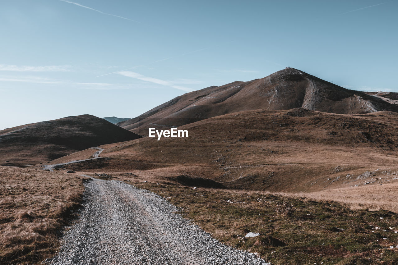 Scenic view of road by mountains against sky