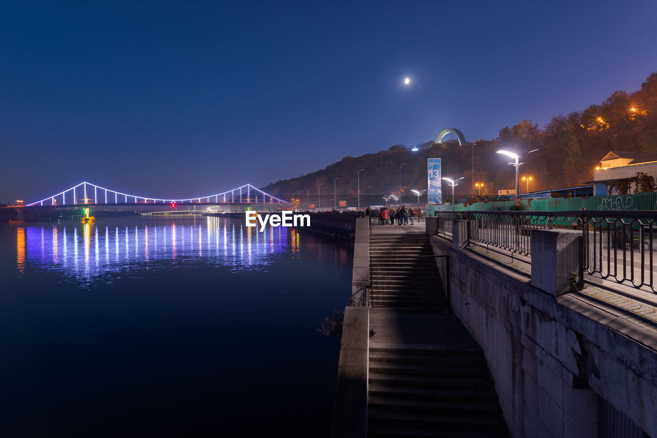 BRIDGE OVER RIVER AGAINST CLEAR SKY AT NIGHT