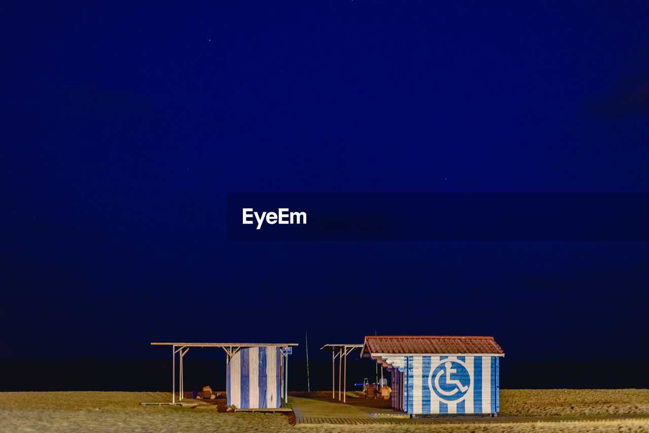 HOODED CHAIRS ON BEACH AGAINST CLEAR BLUE SKY