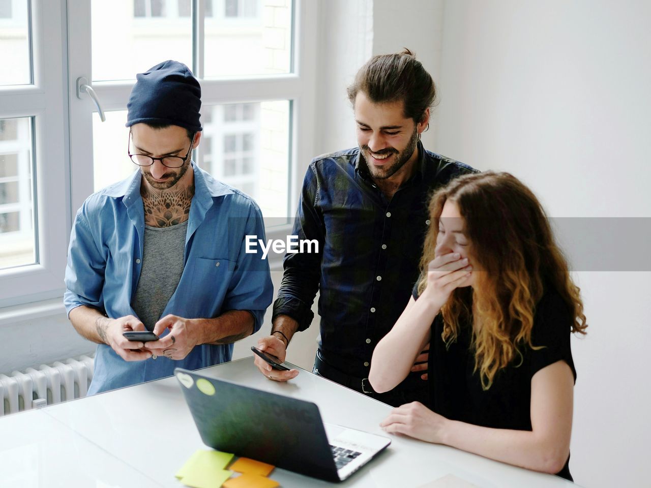 Three people looking at laptop in office meeting