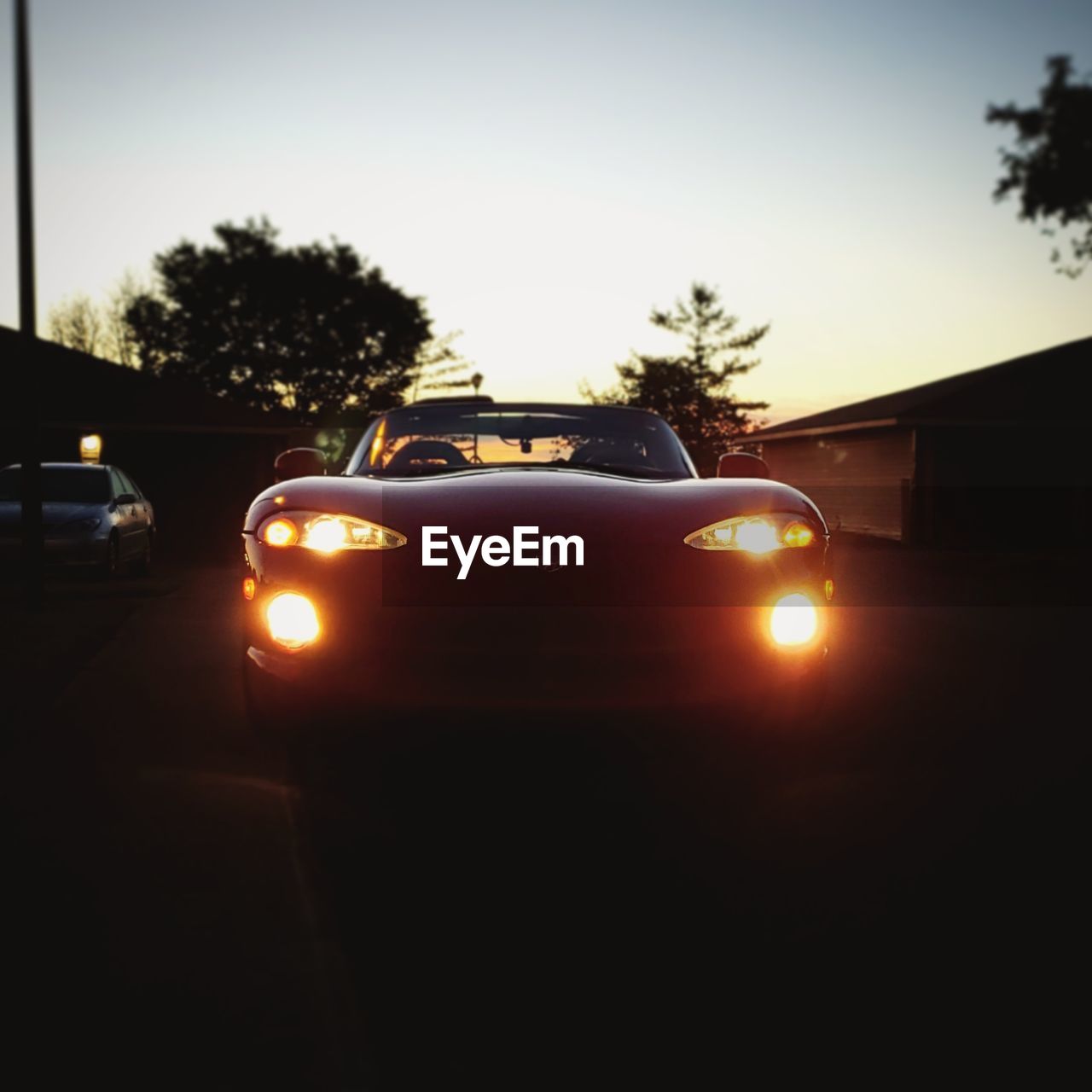 CAR ON ILLUMINATED STREET AGAINST SKY