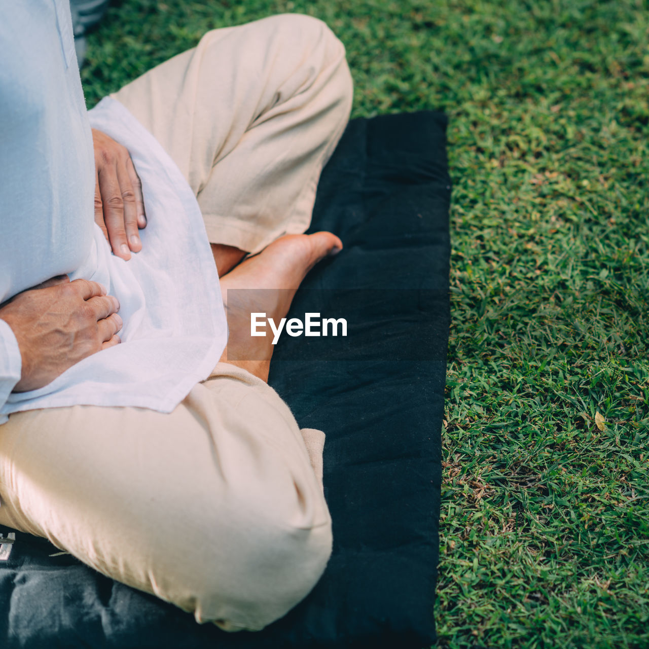 Male therapist performing reiki therapy self treatment holding hands over his stomach. 