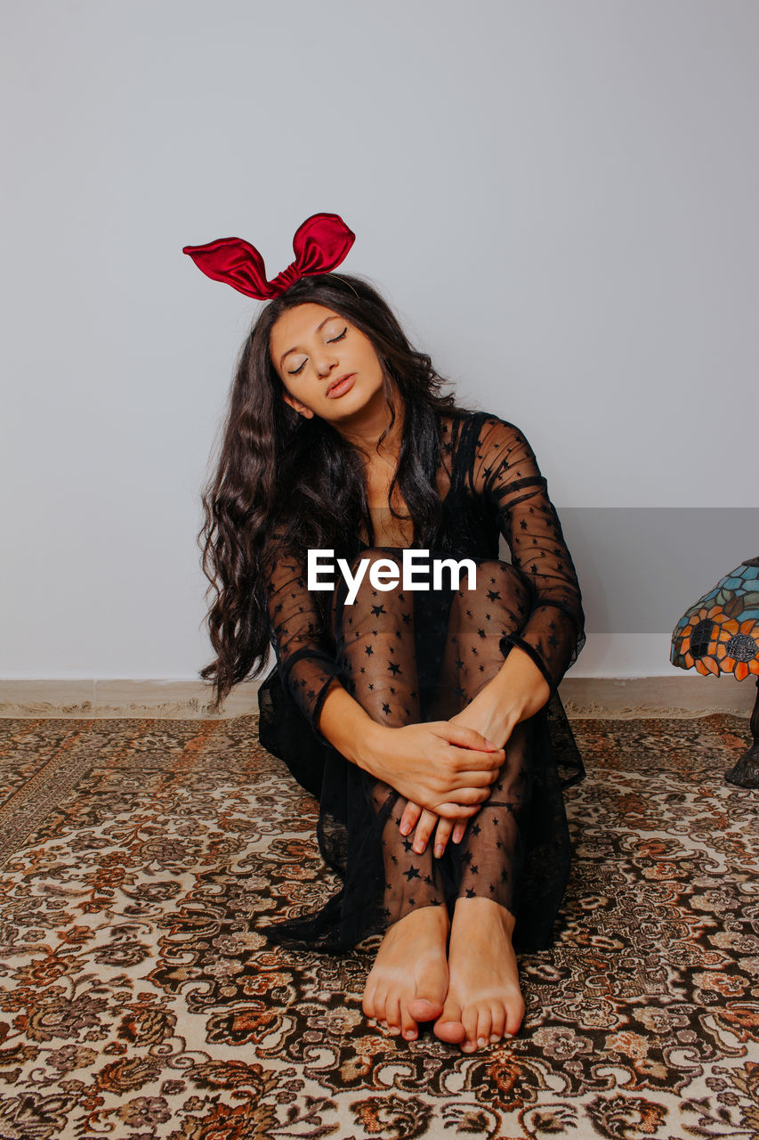 Young woman with red bow looking down. easter themed fashion photography. hair accessory.