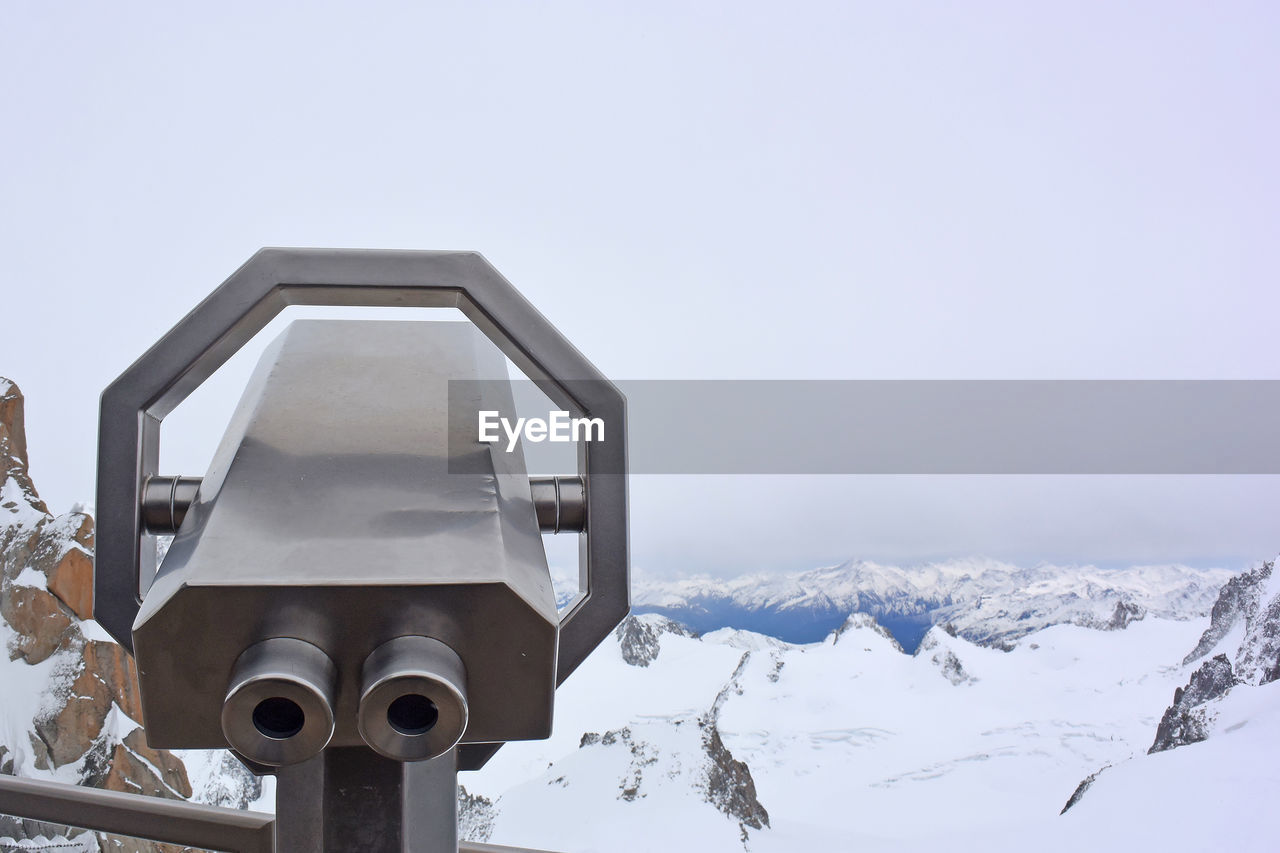 Binoculars on snow covered mountain against clear sky