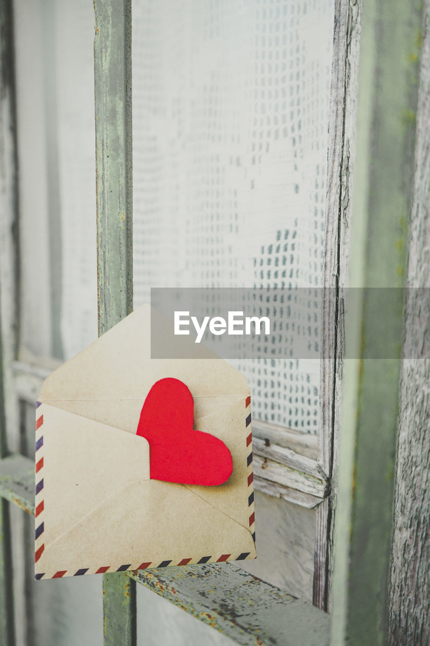 CLOSE-UP OF HEART SHAPE MADE ON PAPER AGAINST WALL