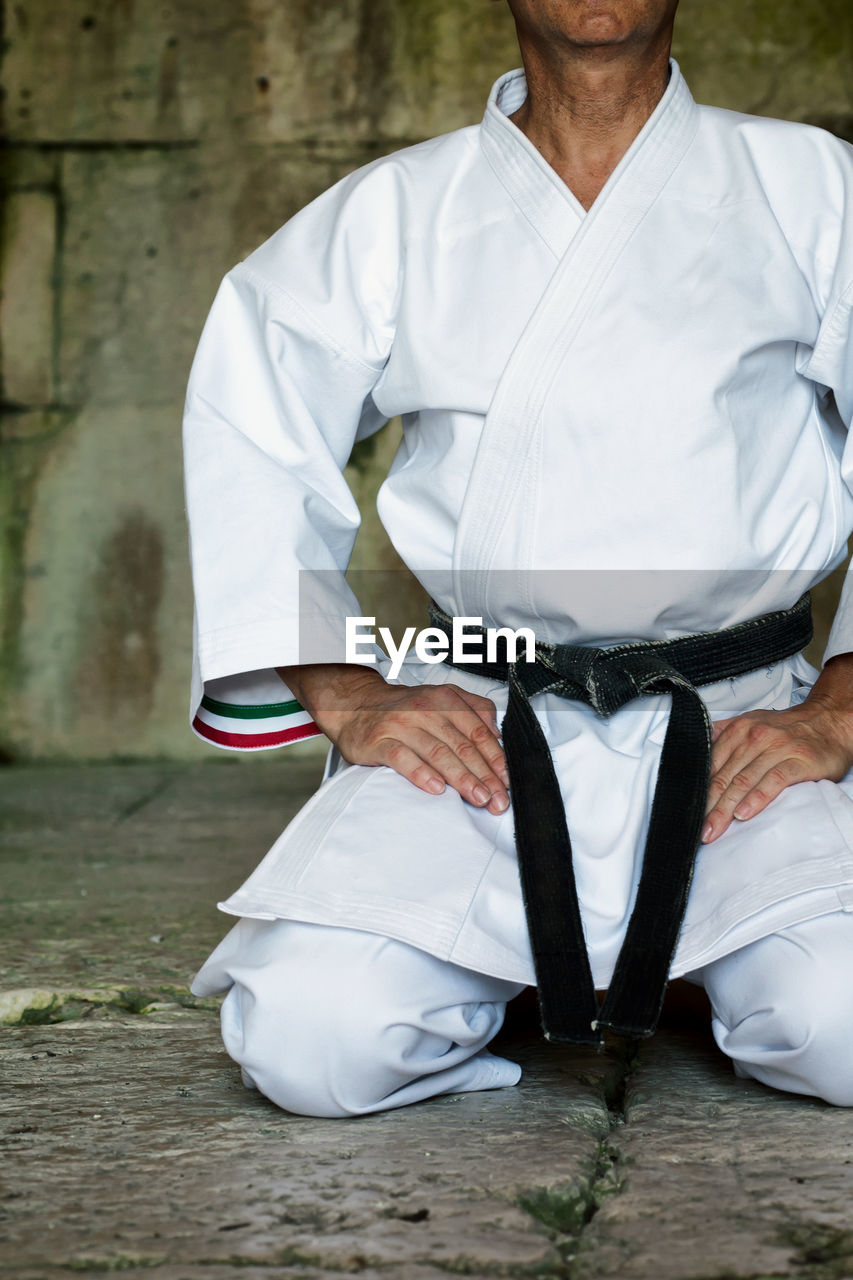 Black belt karate man sit on a position to start or finish practicing.