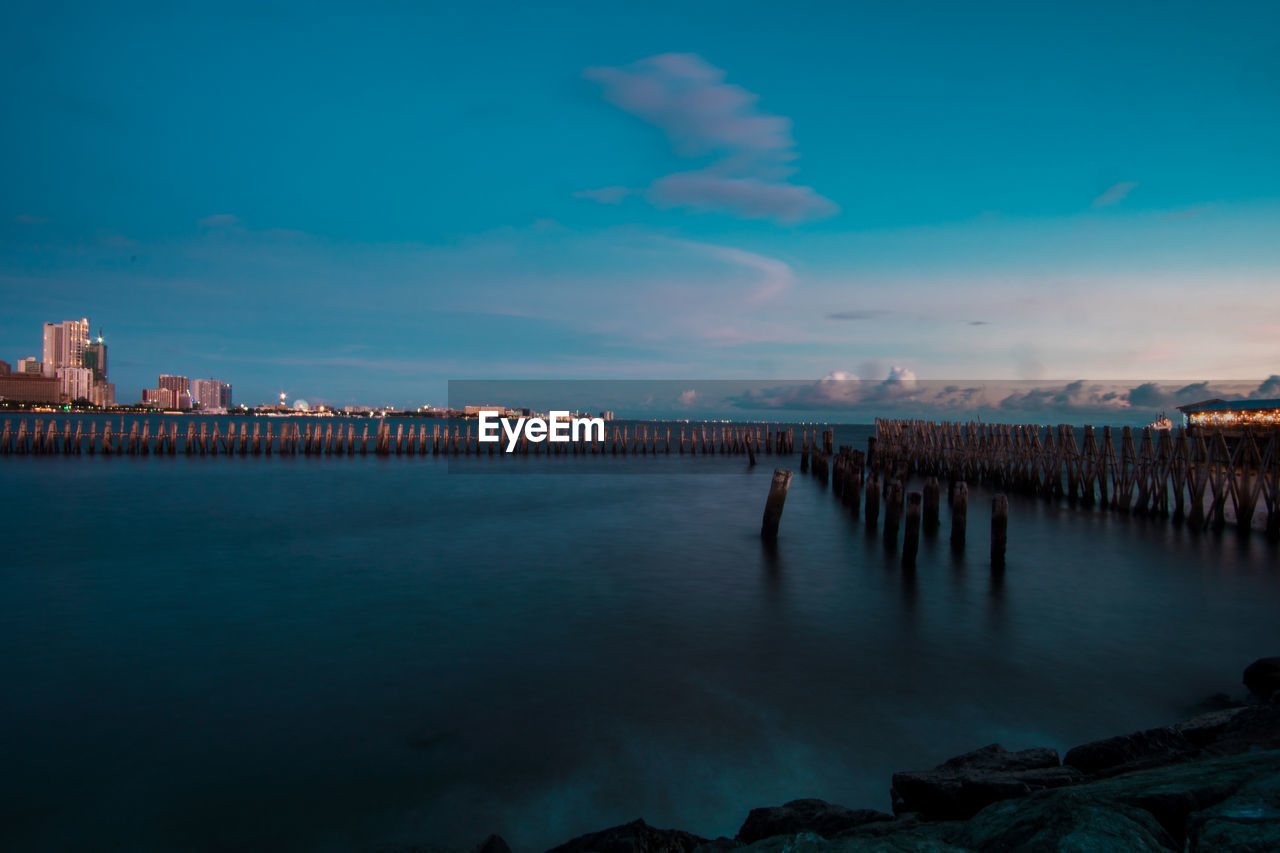 Scenic view of sea and buildings against sky at dusk
