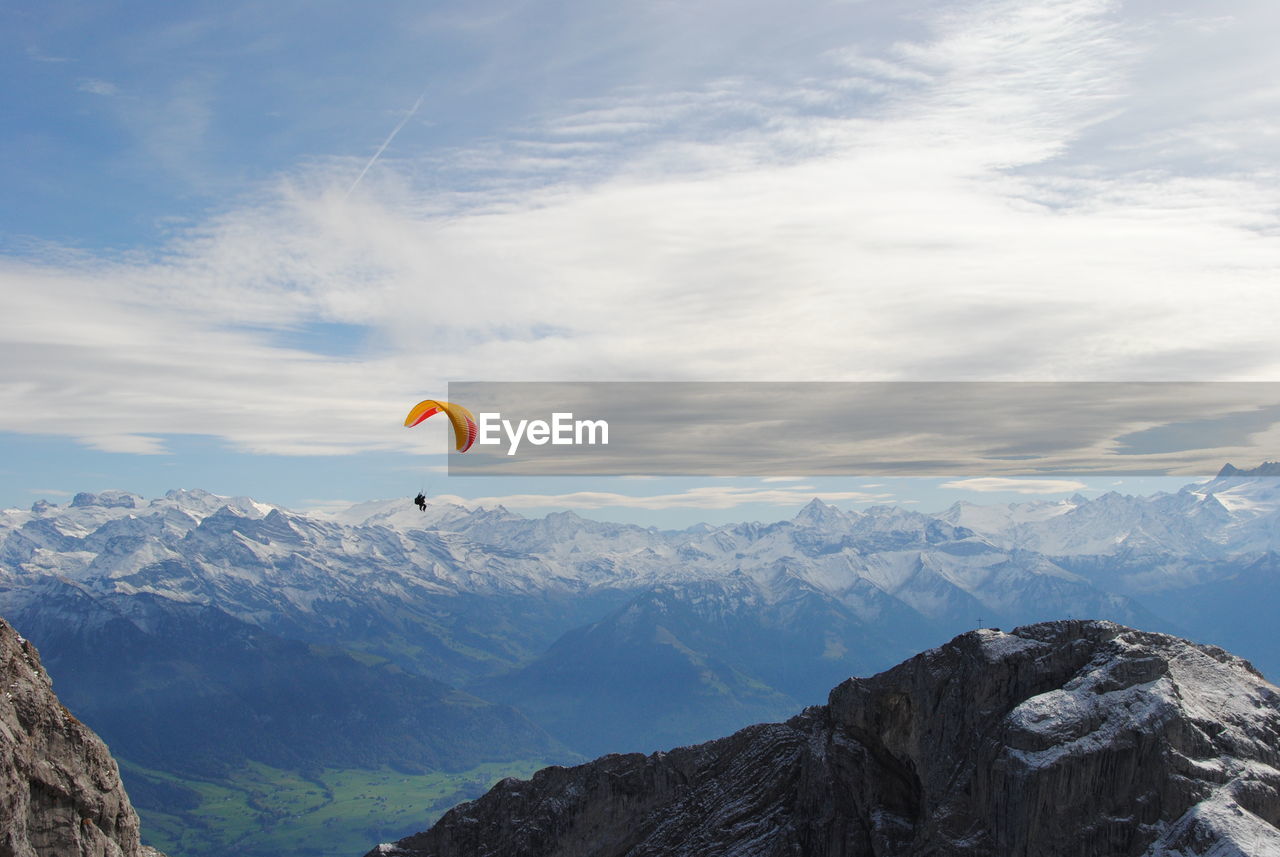 LOW ANGLE VIEW OF PERSON PARAGLIDING AGAINST MOUNTAIN