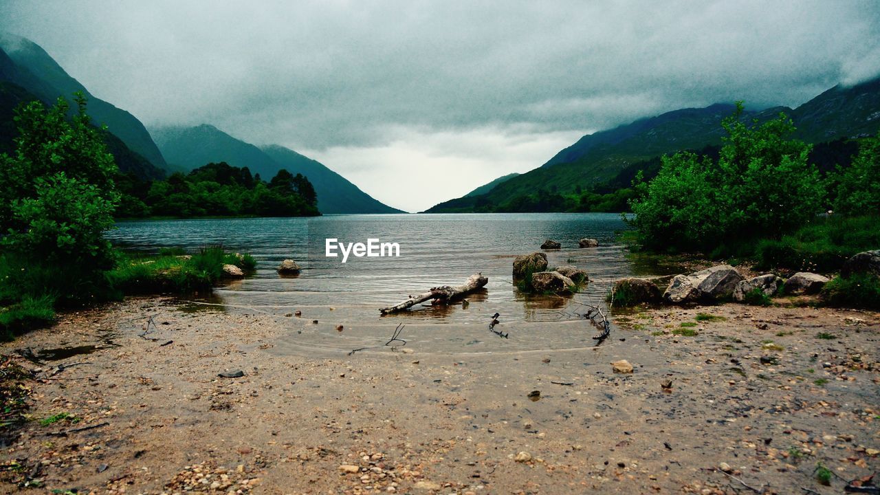 Idyllic view of calm lake against cloudy sky