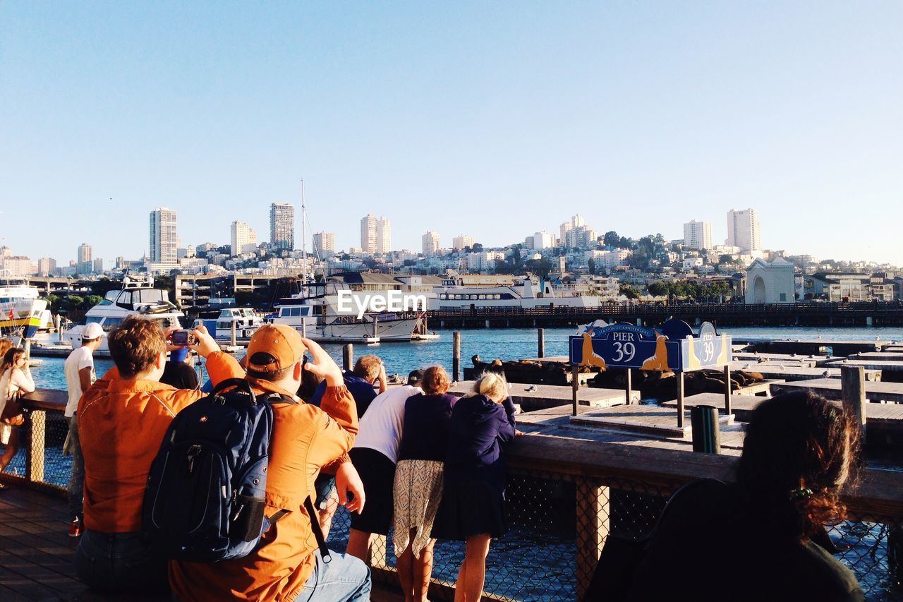 Tourists at pier 39 against clear sky
