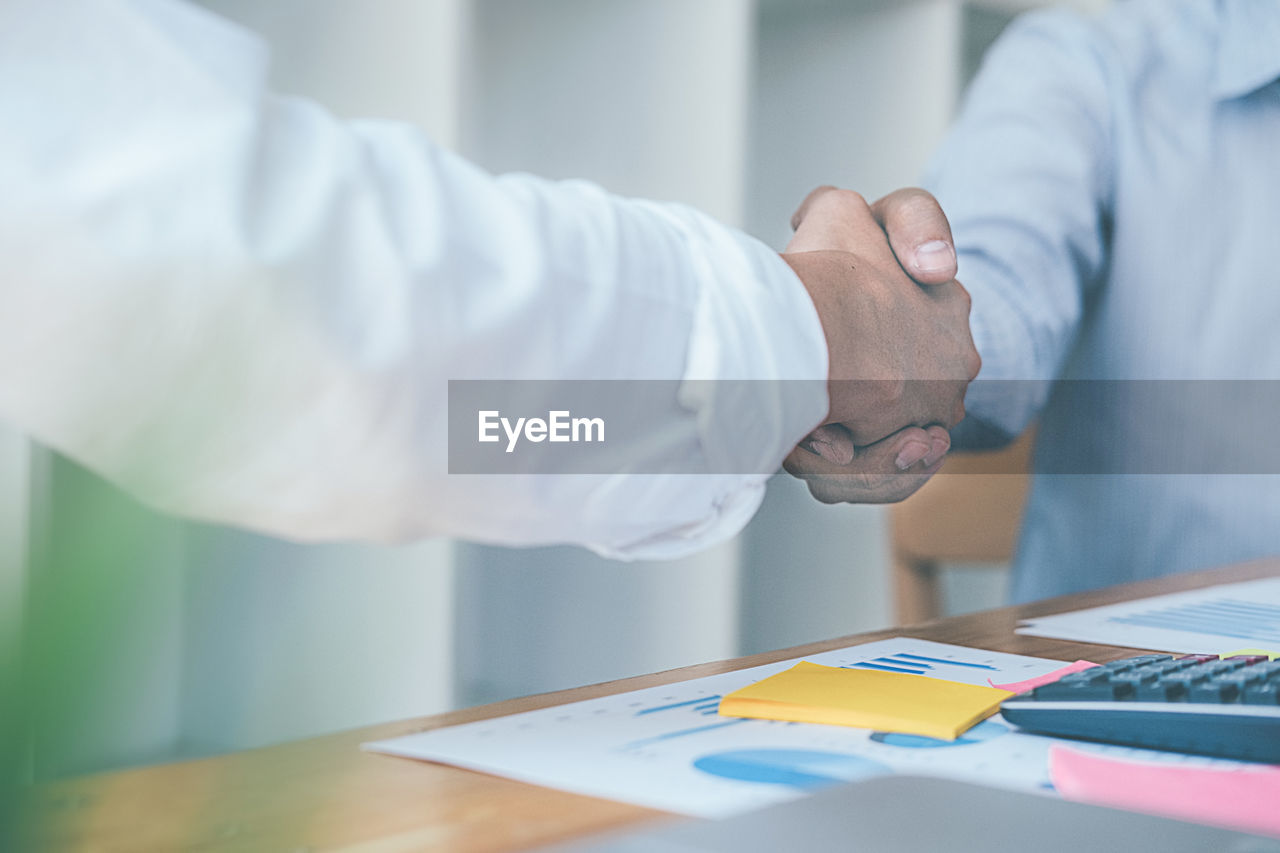 Midsection of businessman giving handshake in office