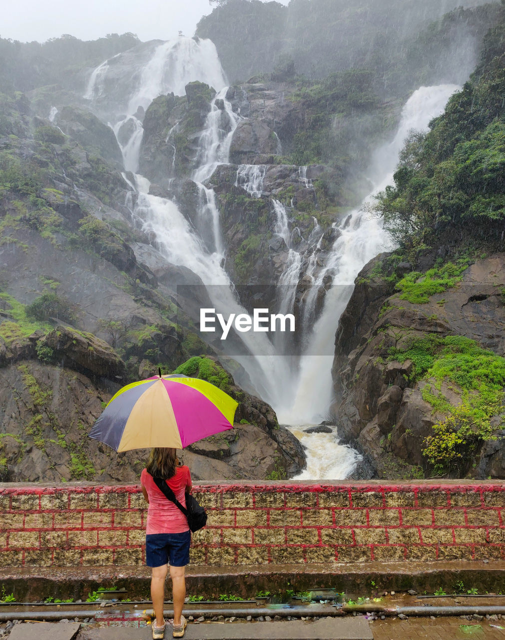 Full length of woman standing by waterfall