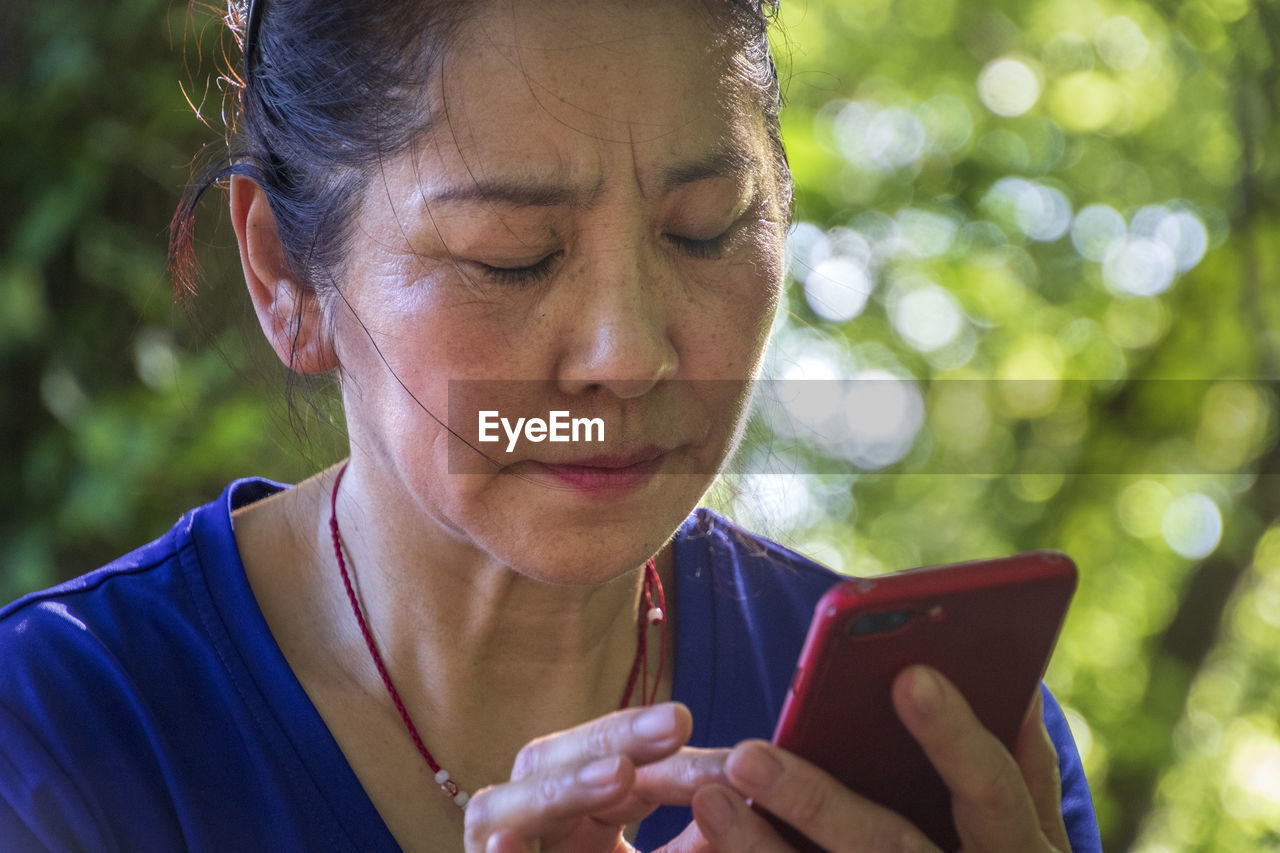 PORTRAIT OF WOMAN HOLDING SMART PHONE OUTDOORS