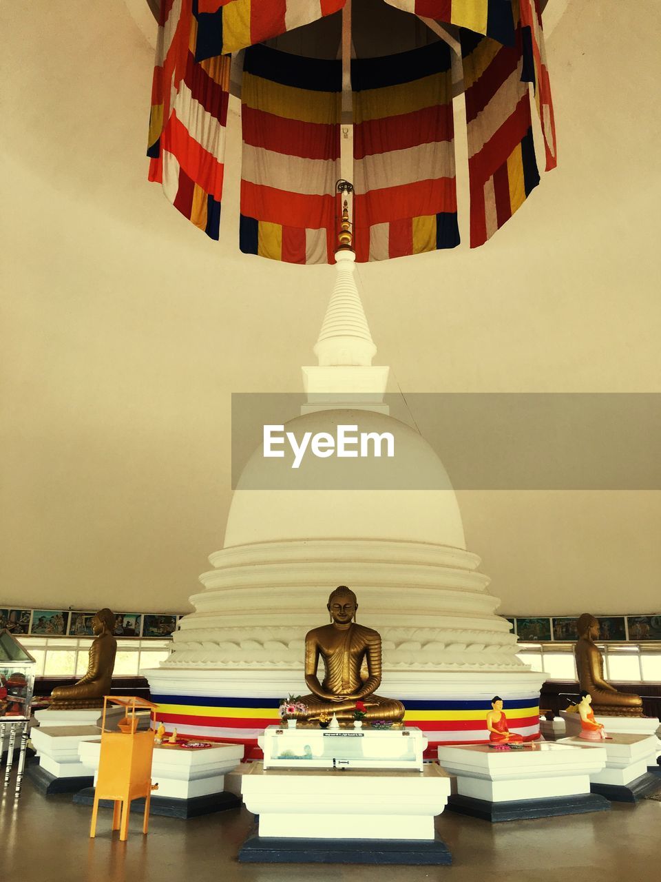 STATUE OF BUDDHA SITTING AGAINST WALL