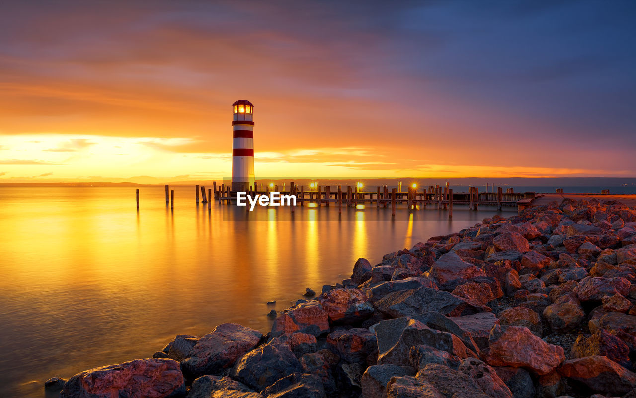 Scenic view of sea against cloudy sky during sunset