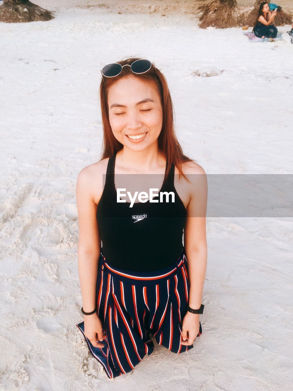 Smiling young woman kneeling on beach