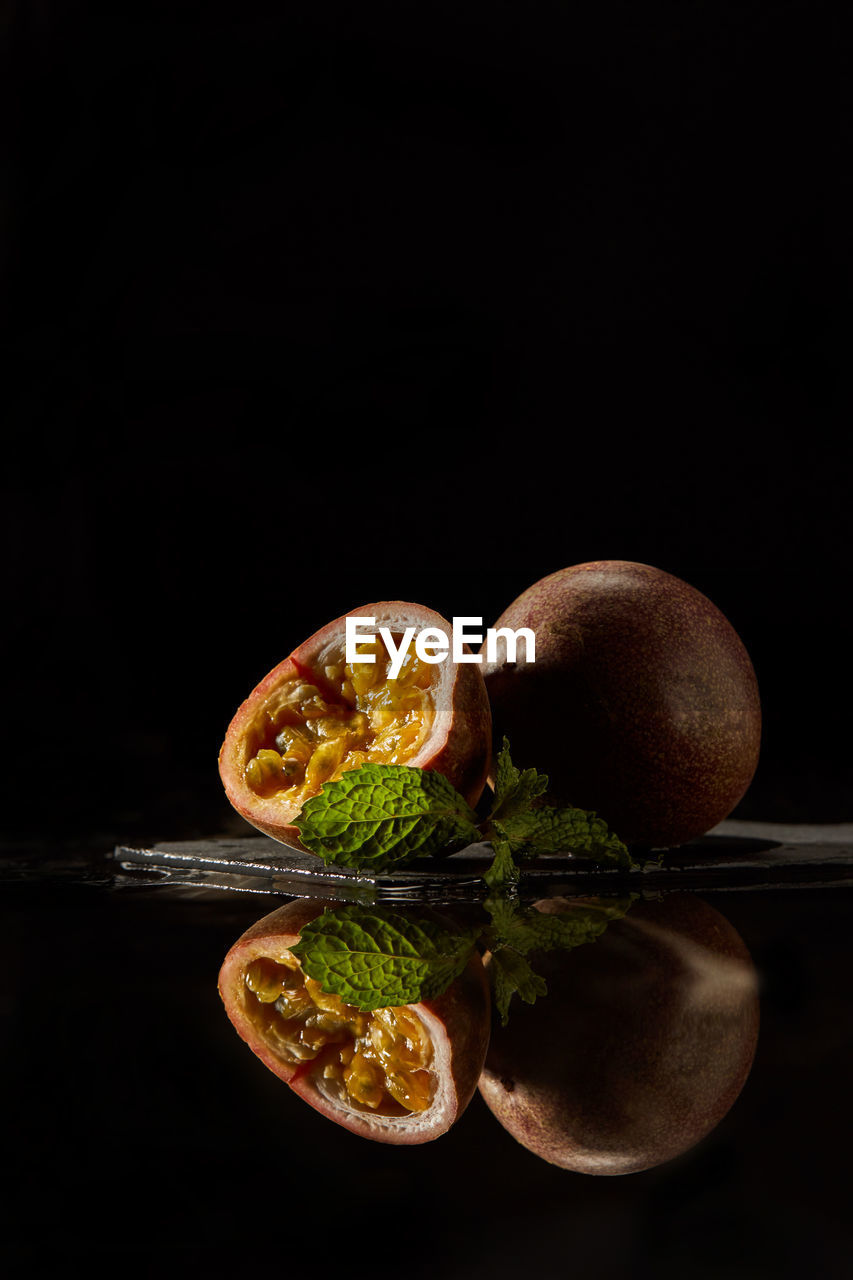 Passion fruit sliced on dark background with reflection. vertical photo