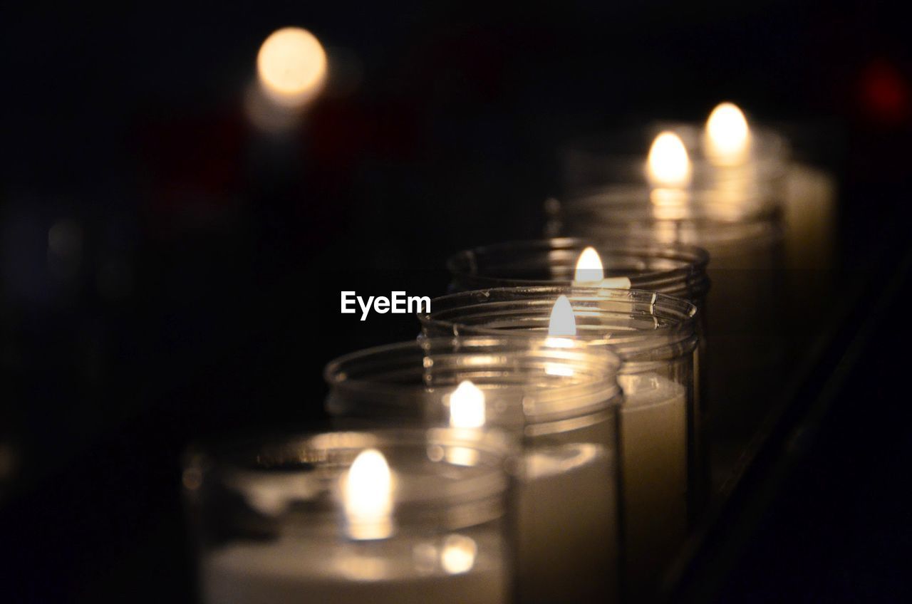 Close-up of lit tea light candles in darkroom