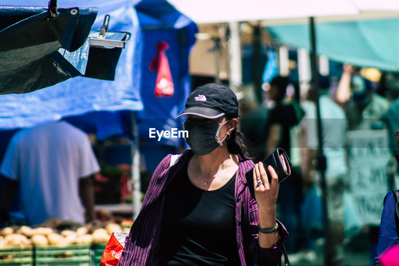 REAR VIEW OF WOMAN HOLDING MOBILE PHONE WHILE STANDING ON LAPTOP