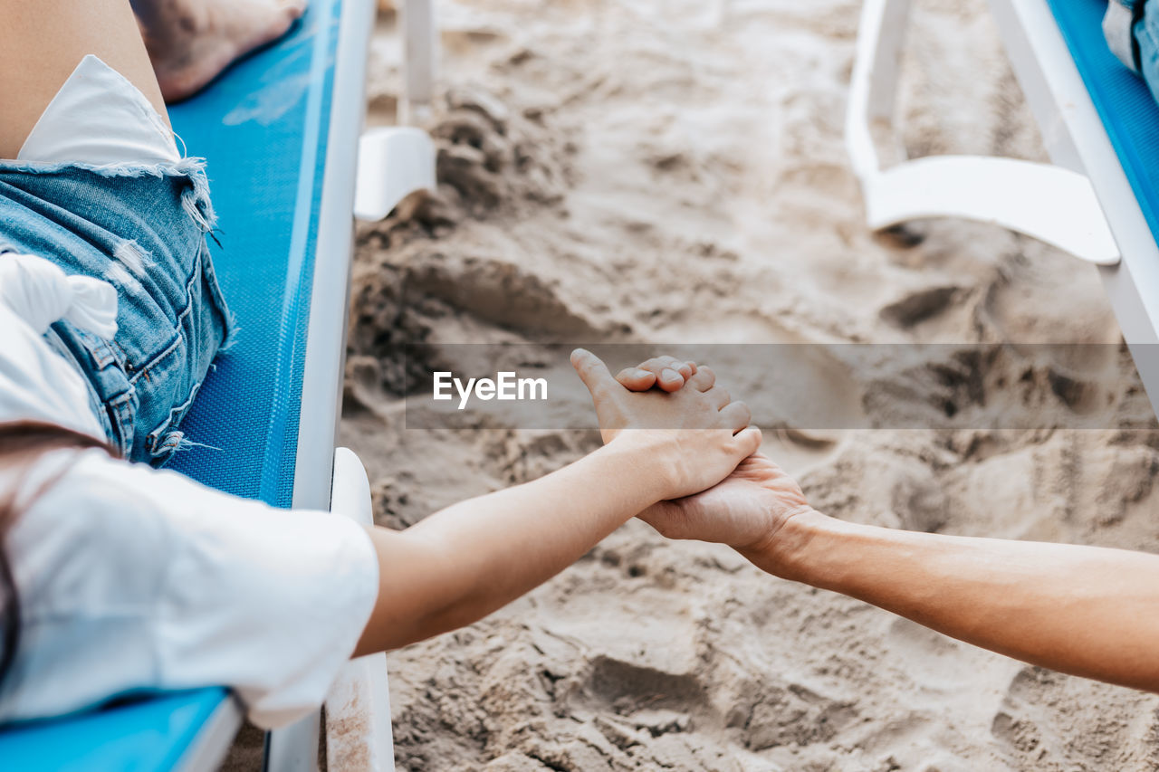 Low section of man holding hands on sand