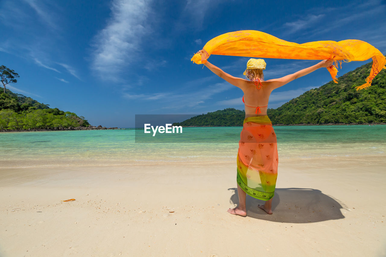 Woman standing at beach against sky