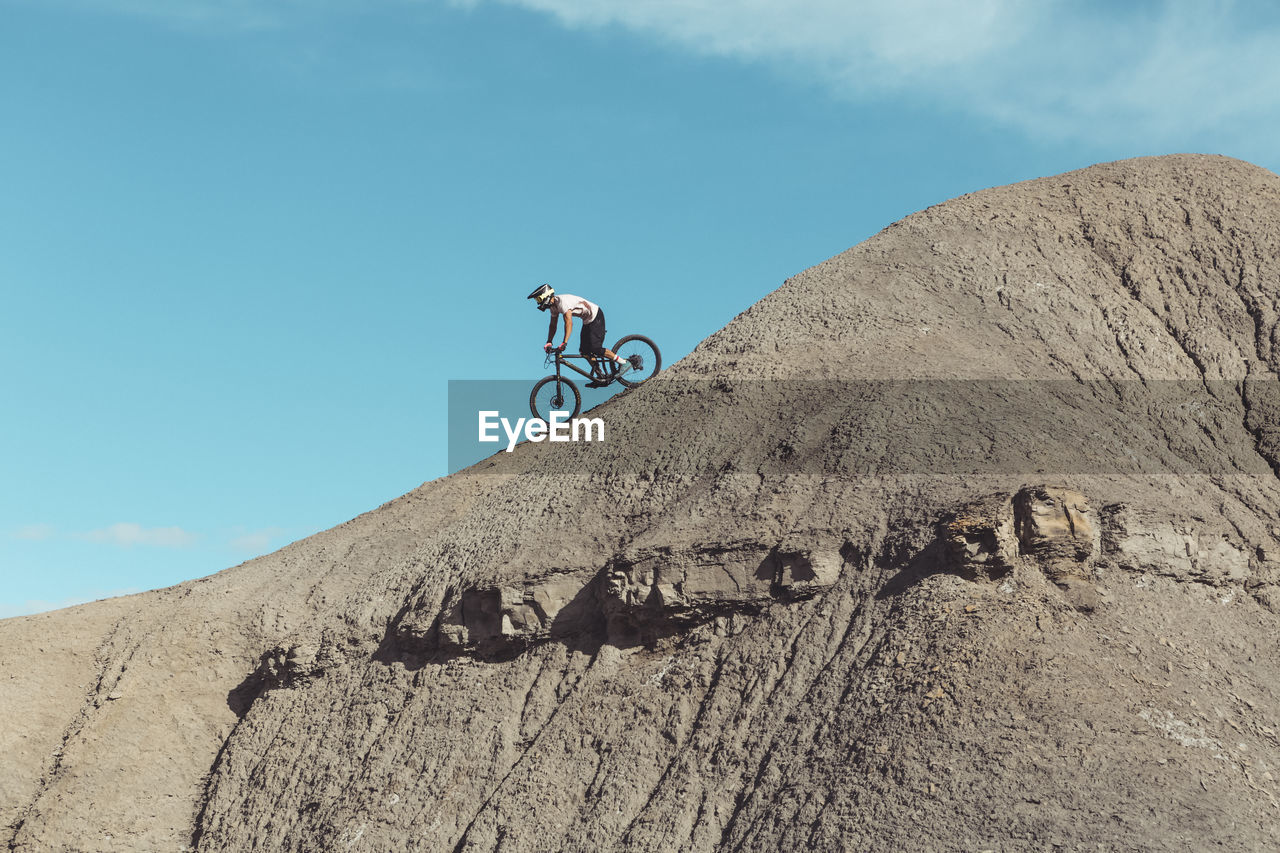 Side view of mountainbiker riding steep desert terrain