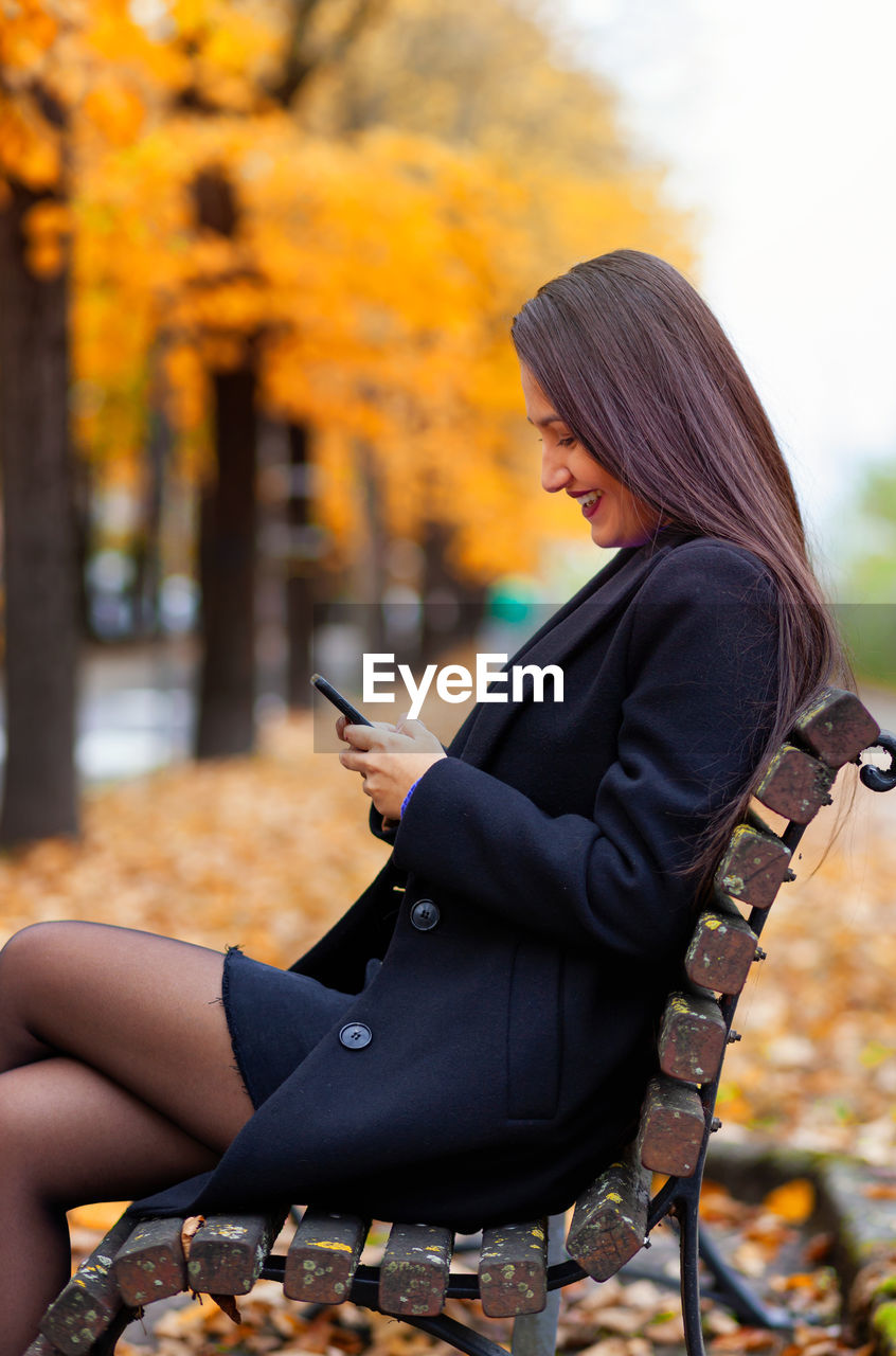 Portrait of a young woman in autumn. scenery with warm light and falling leaves. 