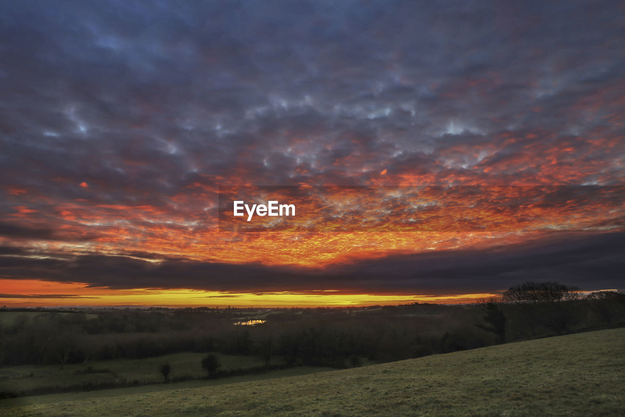 SCENIC VIEW OF DRAMATIC SKY OVER LANDSCAPE DURING SUNSET