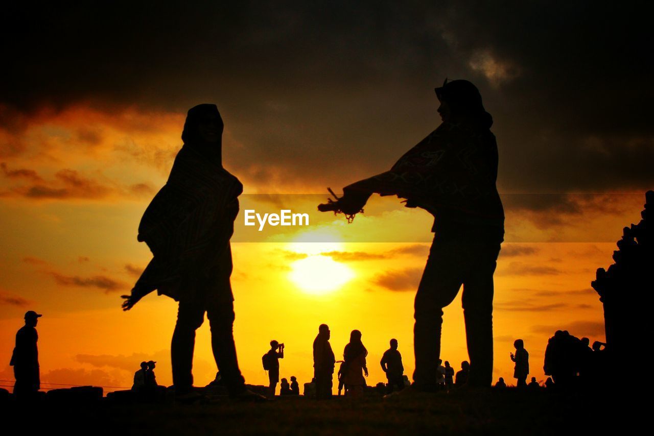 Silhouette people standing against sky during sunset