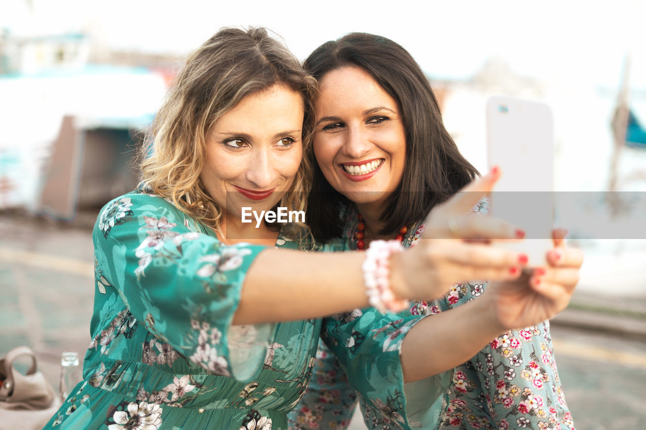 Smiling women taking selfie while standing outdoors