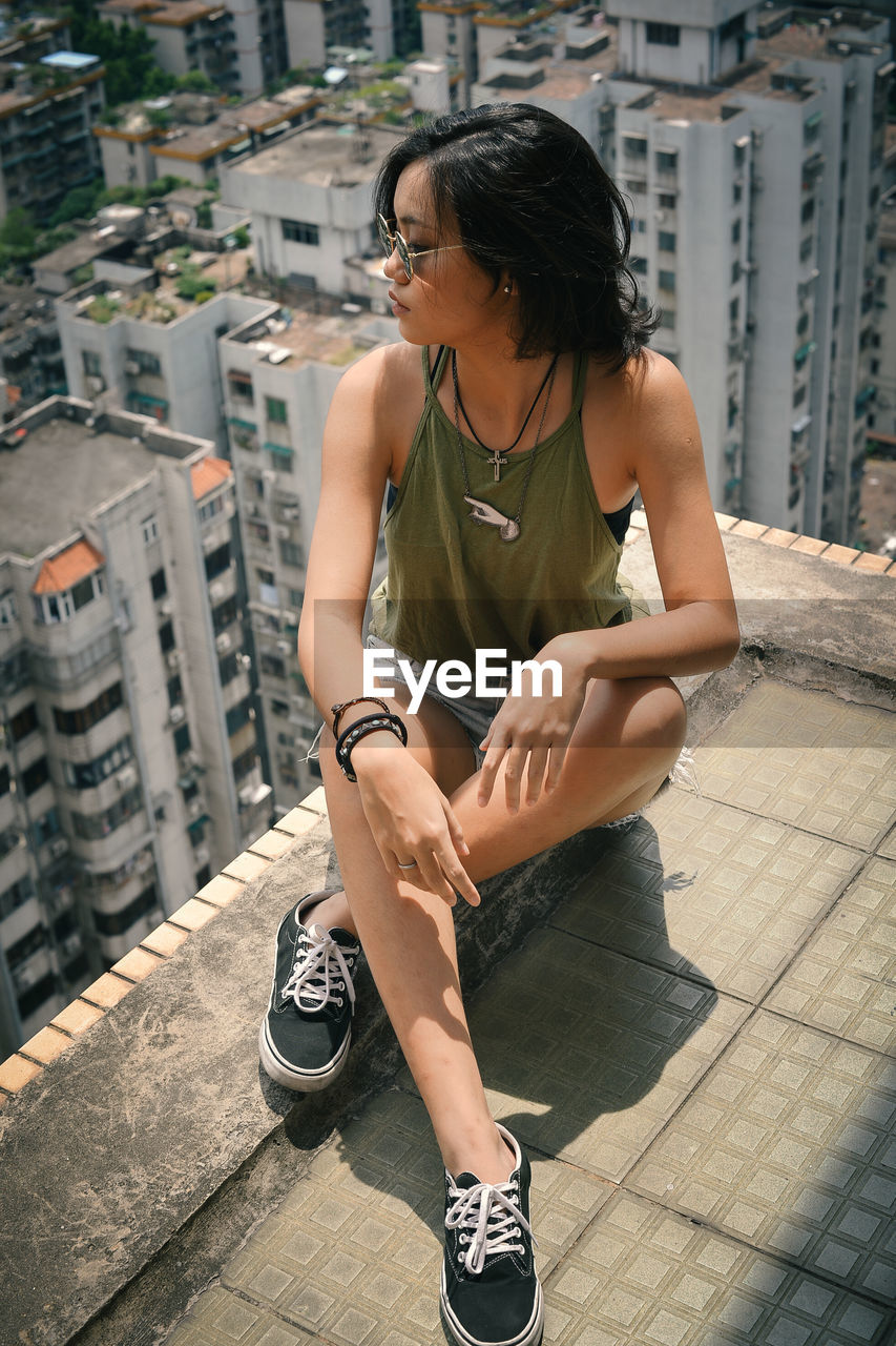 FULL LENGTH OF WOMAN SITTING IN CITY BUILDINGS