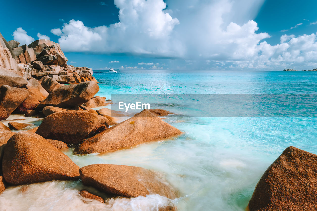 Rocks by sea against cloudy sky