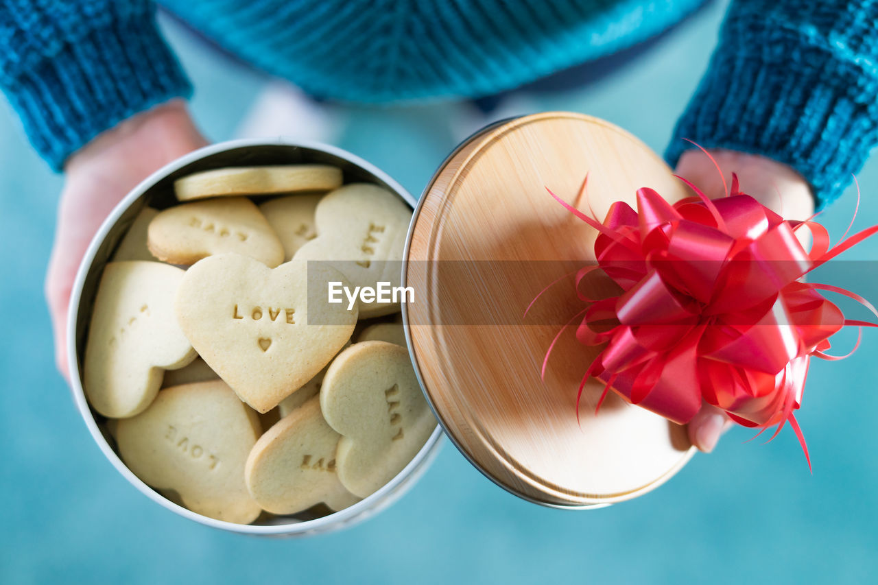 HIGH ANGLE VIEW OF HAND HOLDING RED CHILI PEPPERS ON WHITE TABLE