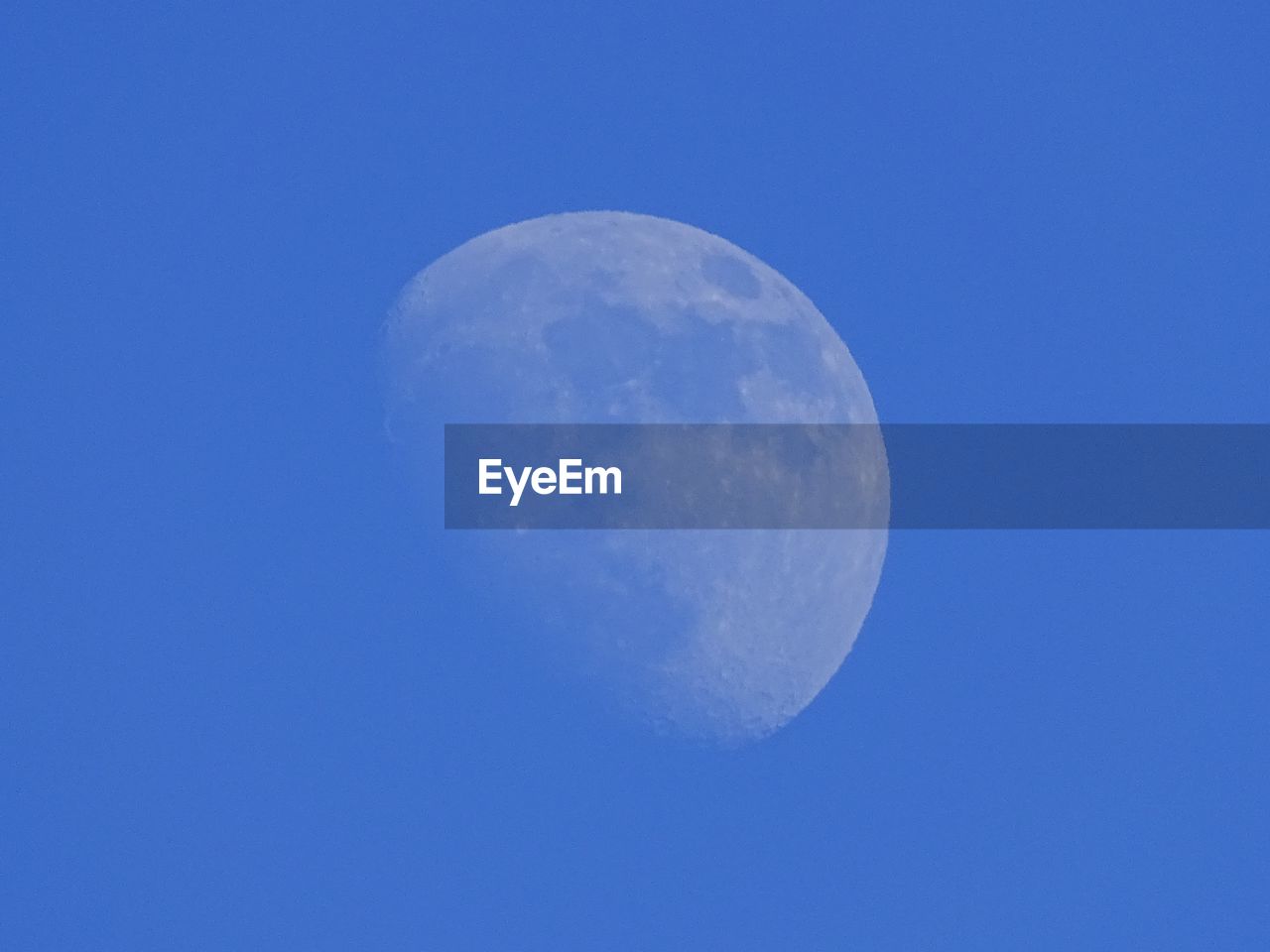 LOW ANGLE VIEW OF MOON AGAINST CLEAR BLUE SKY AT NIGHT