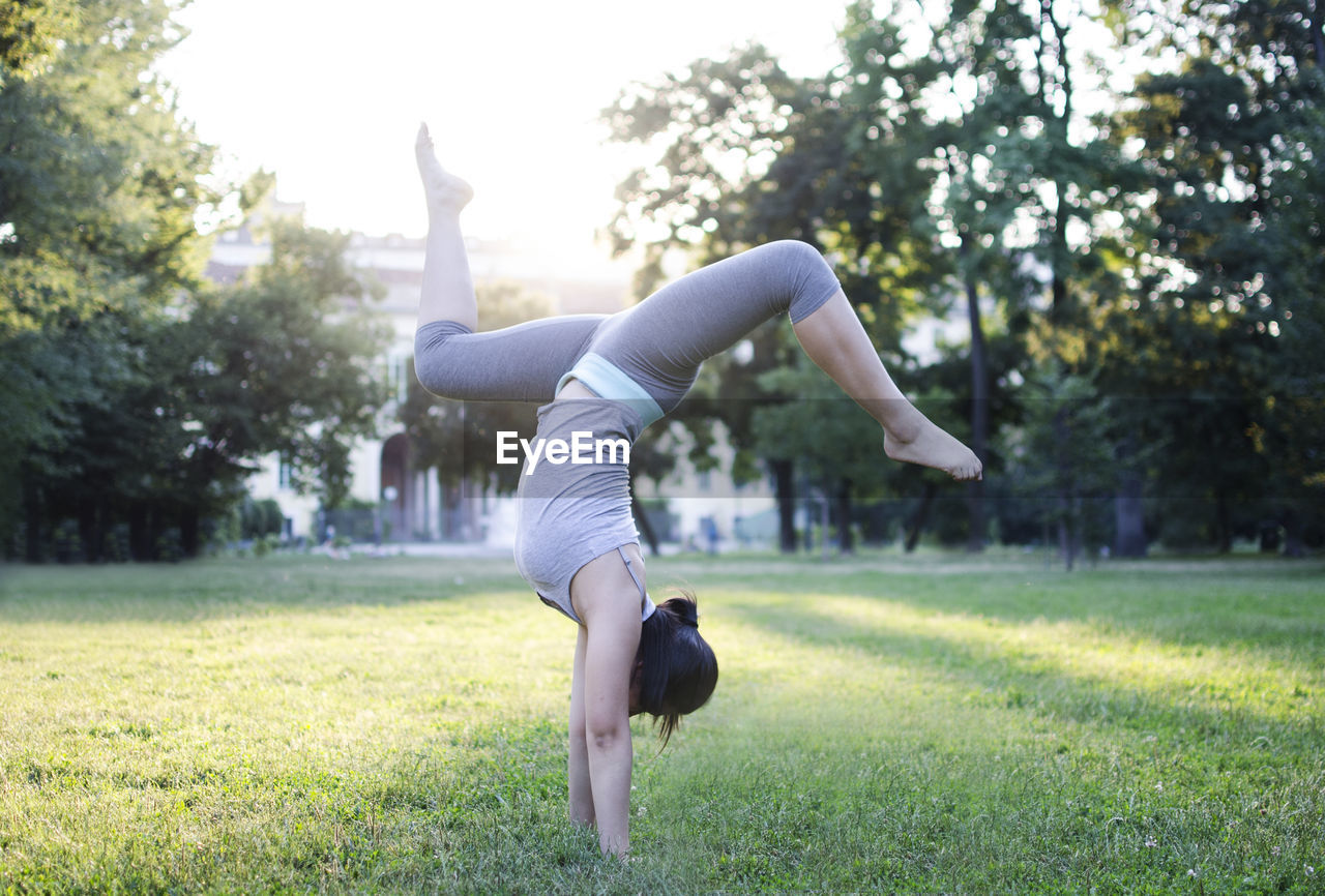 Full length of young woman doing handstand in park