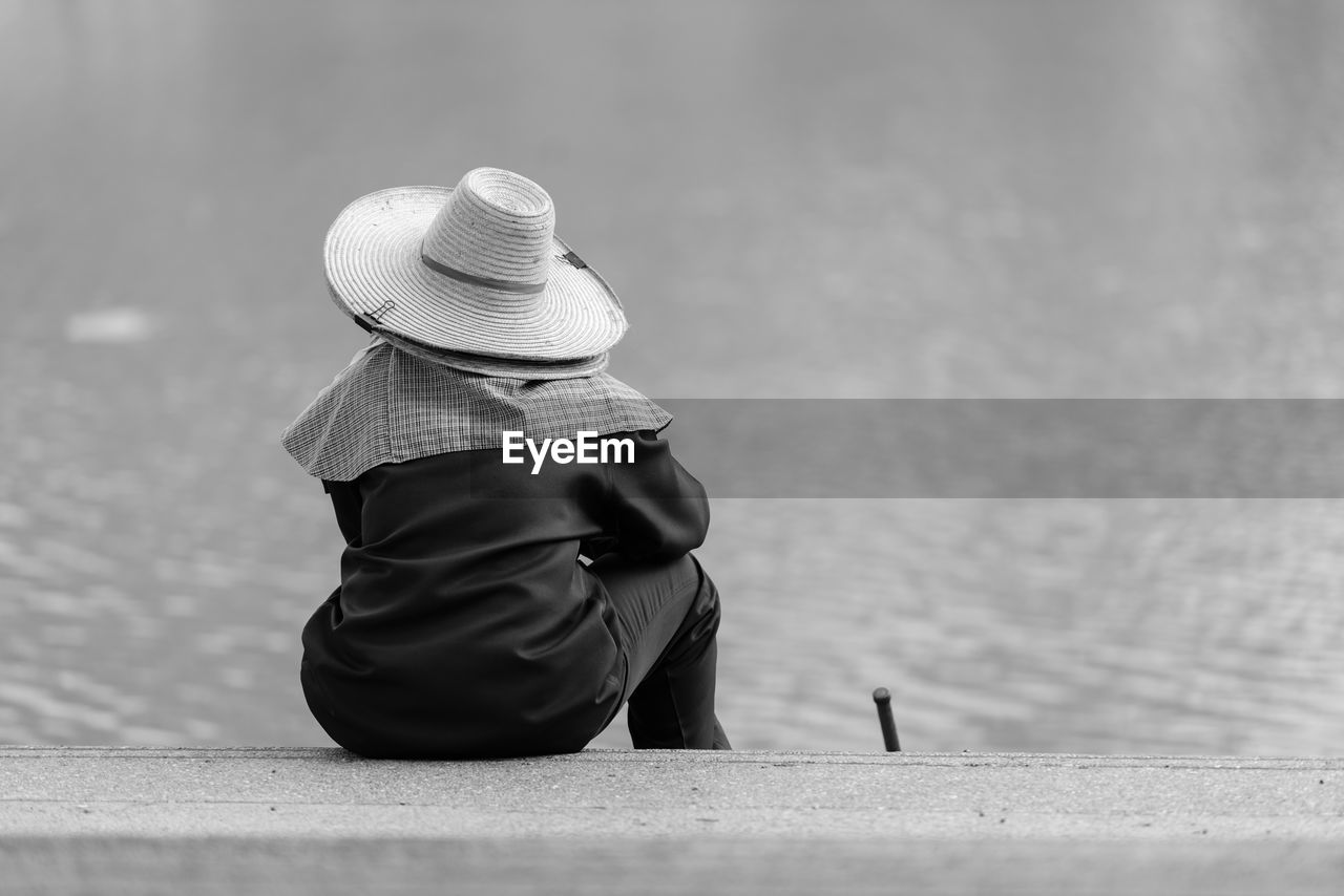 Rear view of woman sitting against wall