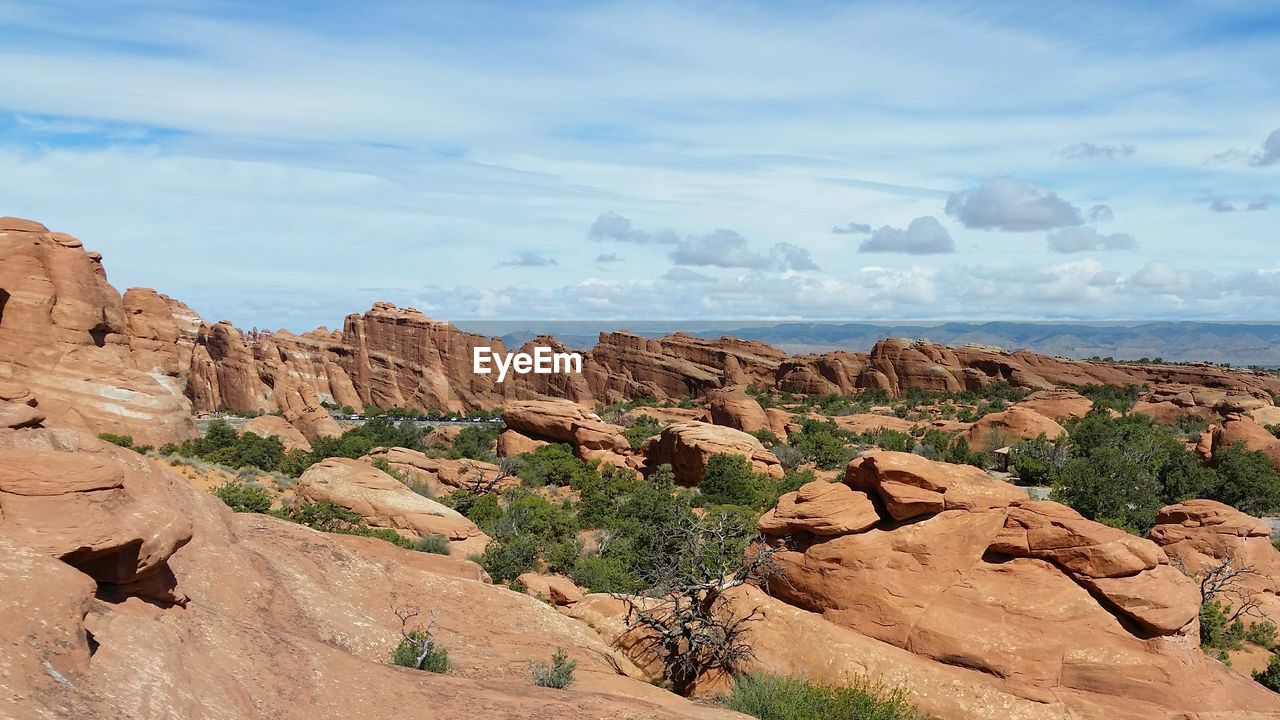 Rock formations on landscape against cloudy sky