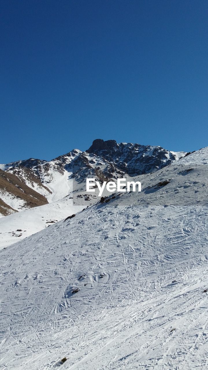 Scenic view of snowcapped mountains against clear blue sky