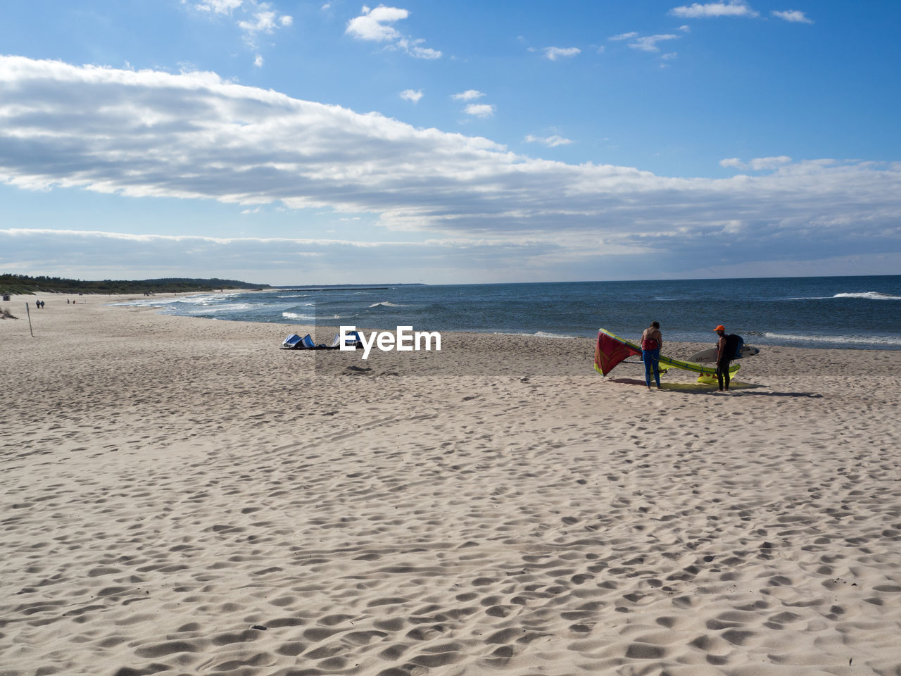 People standing at sandy beach against sky