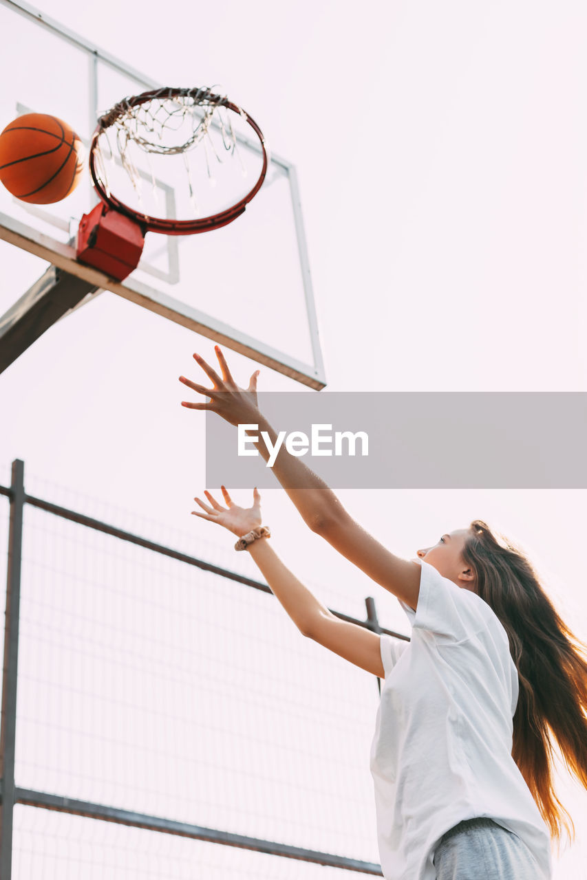 A young girl throws a ball into the basket and plays basketball. basketball, sports, game