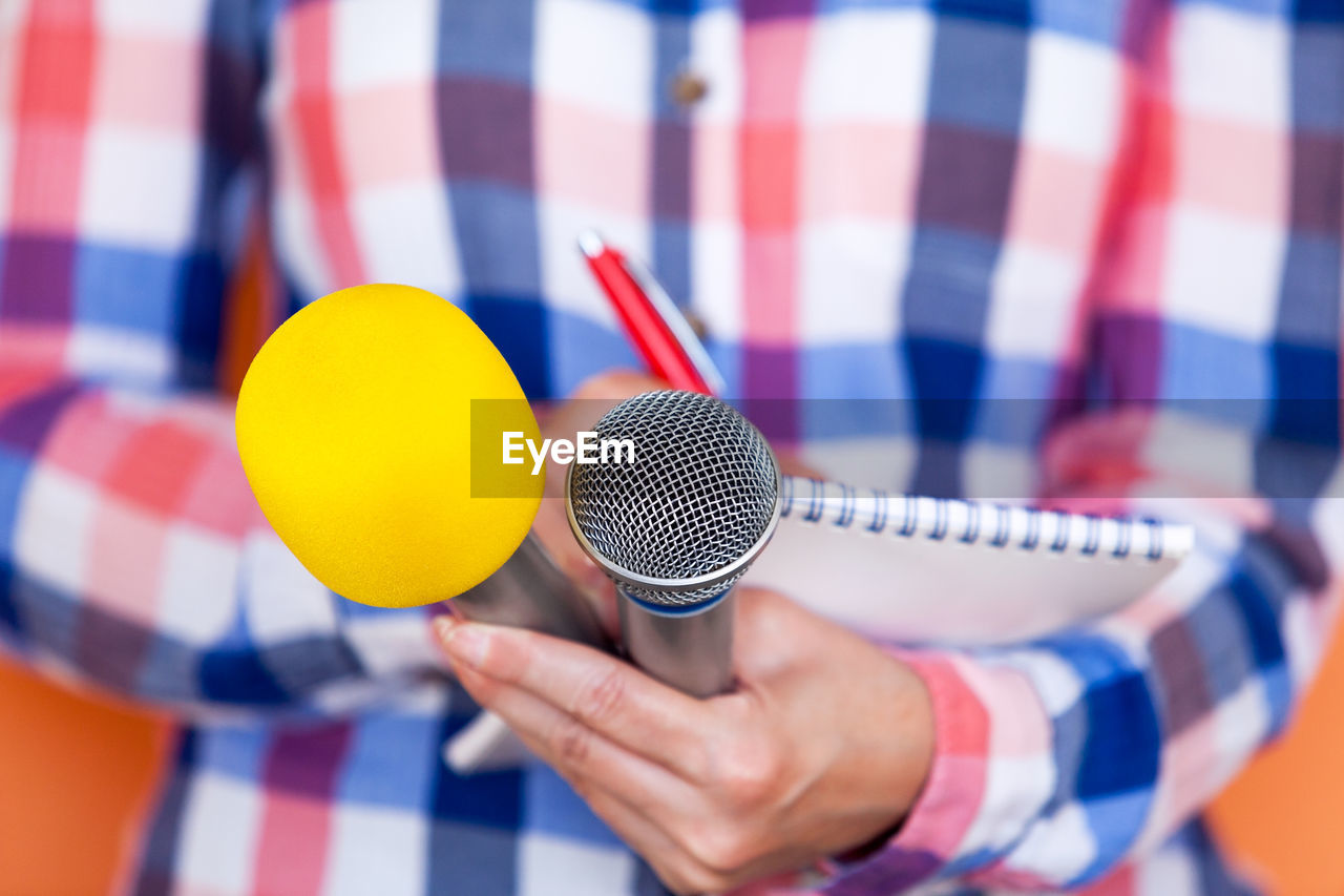 Midsection of man holding microphones