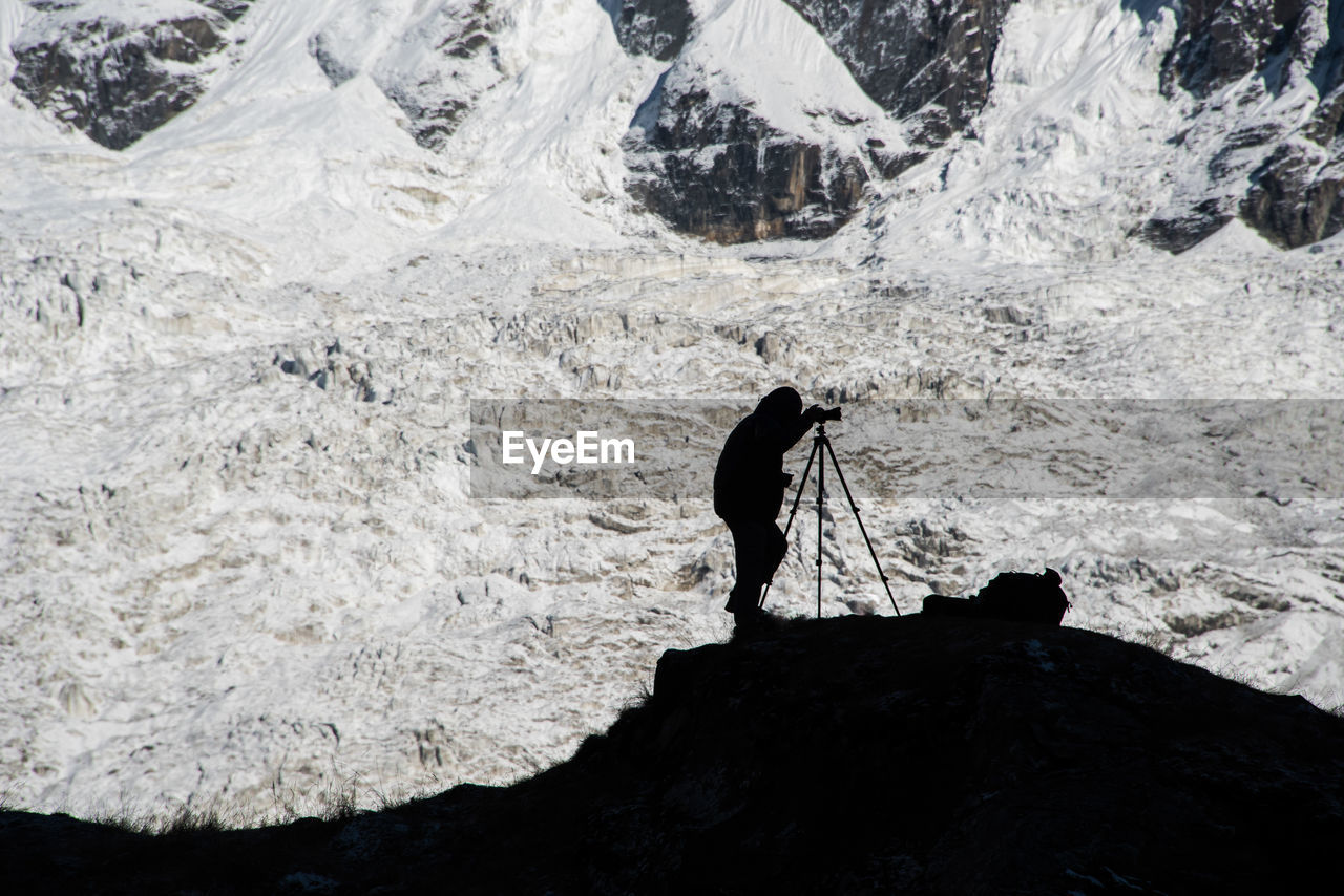 A photographer in annapurna sanctuary in nepal capturing the early morning on the distant mountains